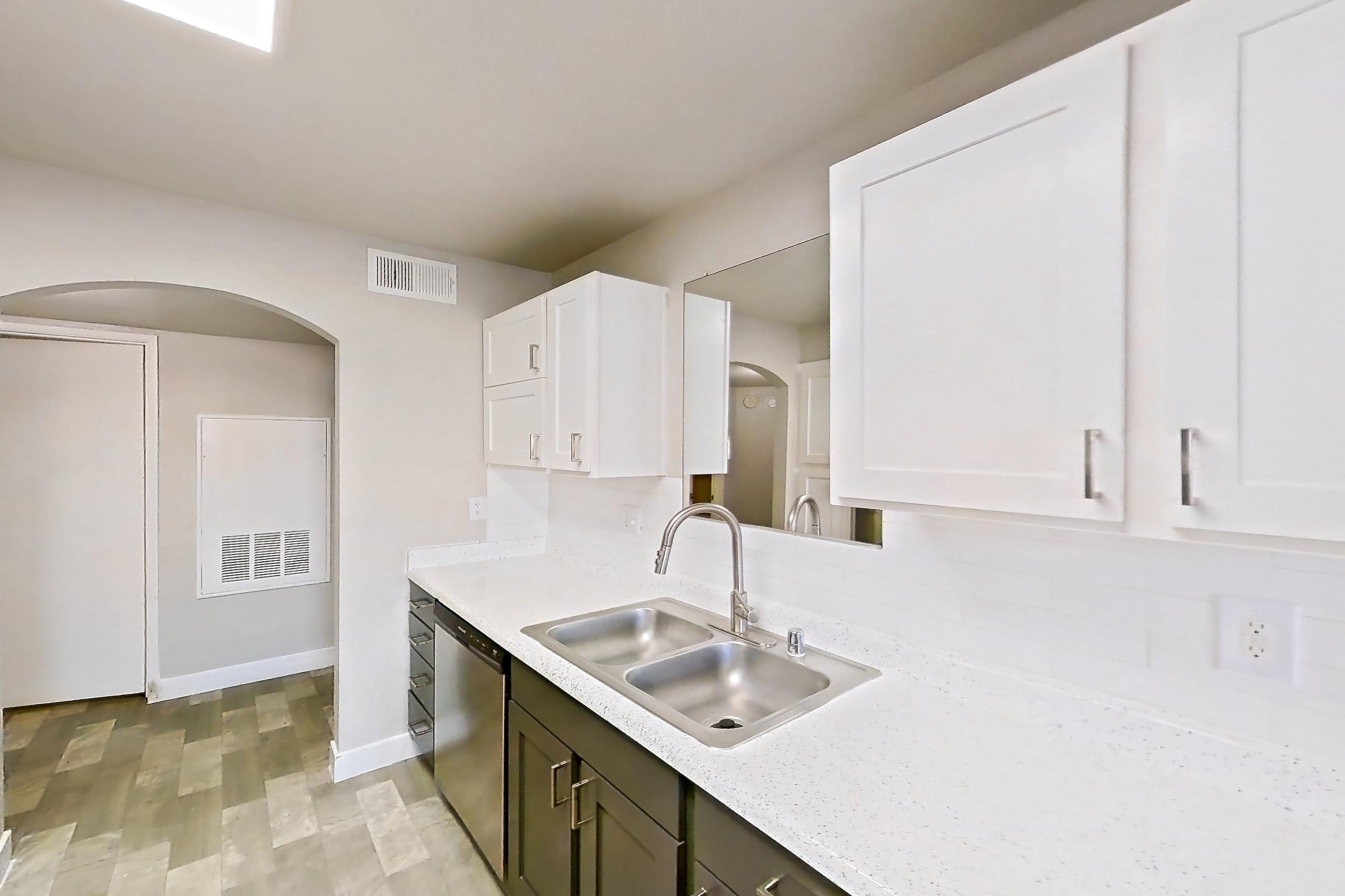 Kitchen with dishwasher, gas range, in-unit laundry, light stone countertops, light wood-finish flooring, microwave, oven/range, refrigerator, and stainless steel appliances, Apartment 1125 at Vintage Pointe