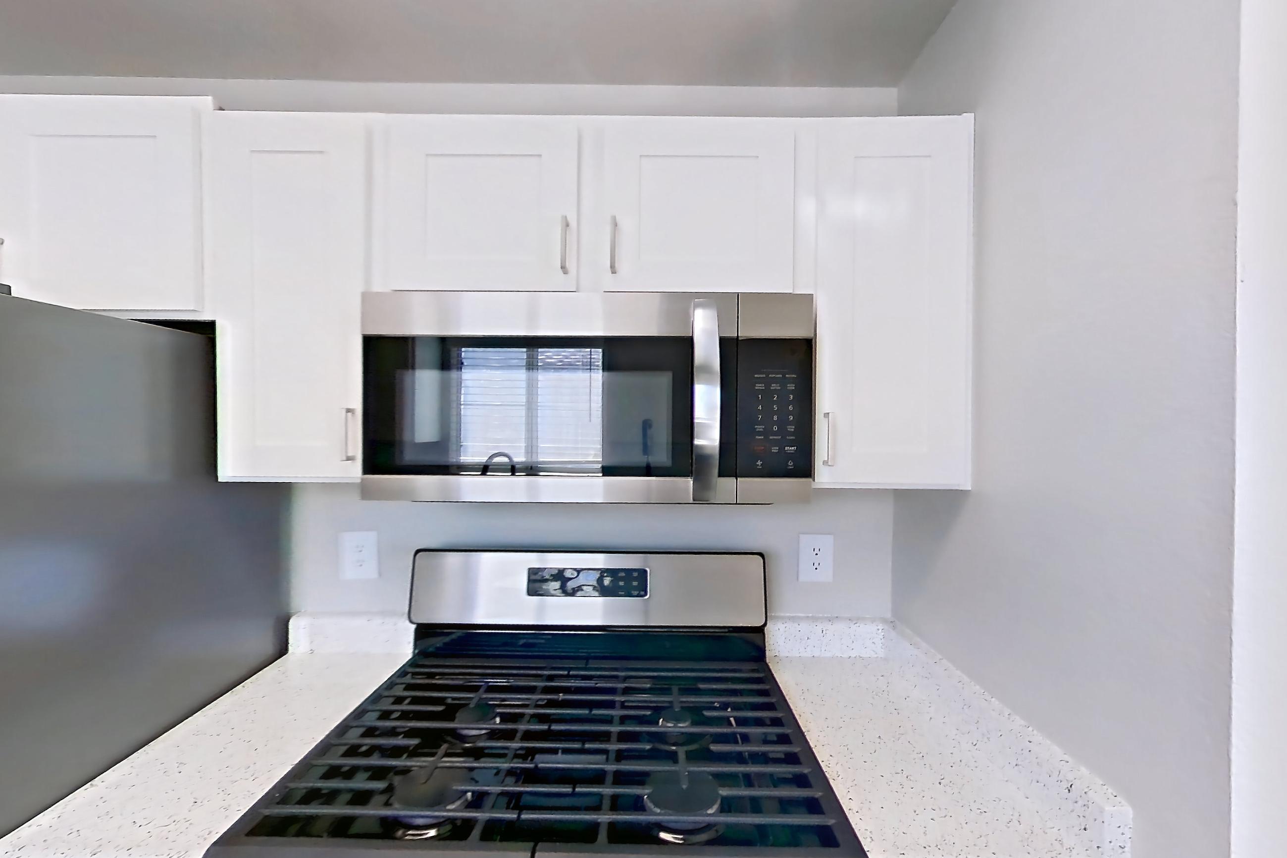 Kitchen with dishwasher, gas range, light countertops, light stone countertops, microwave, oven/range, refrigerator, and stainless steel appliances, Apartment 2004 at Vintage Pointe