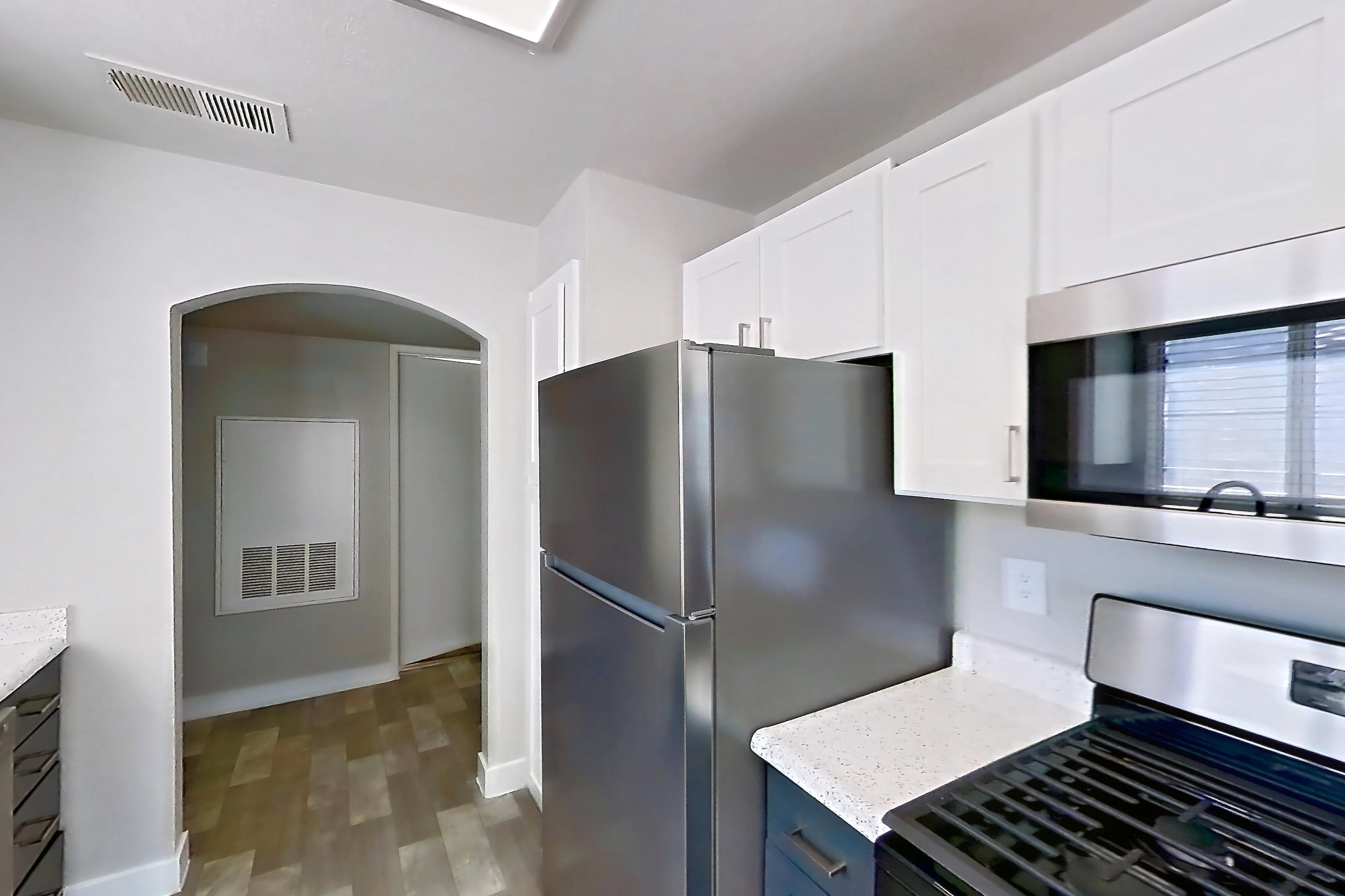 Kitchen with dishwasher, gas range, light countertops, light stone countertops, microwave, oven/range, refrigerator, and stainless steel appliances, Apartment 2004 at Vintage Pointe