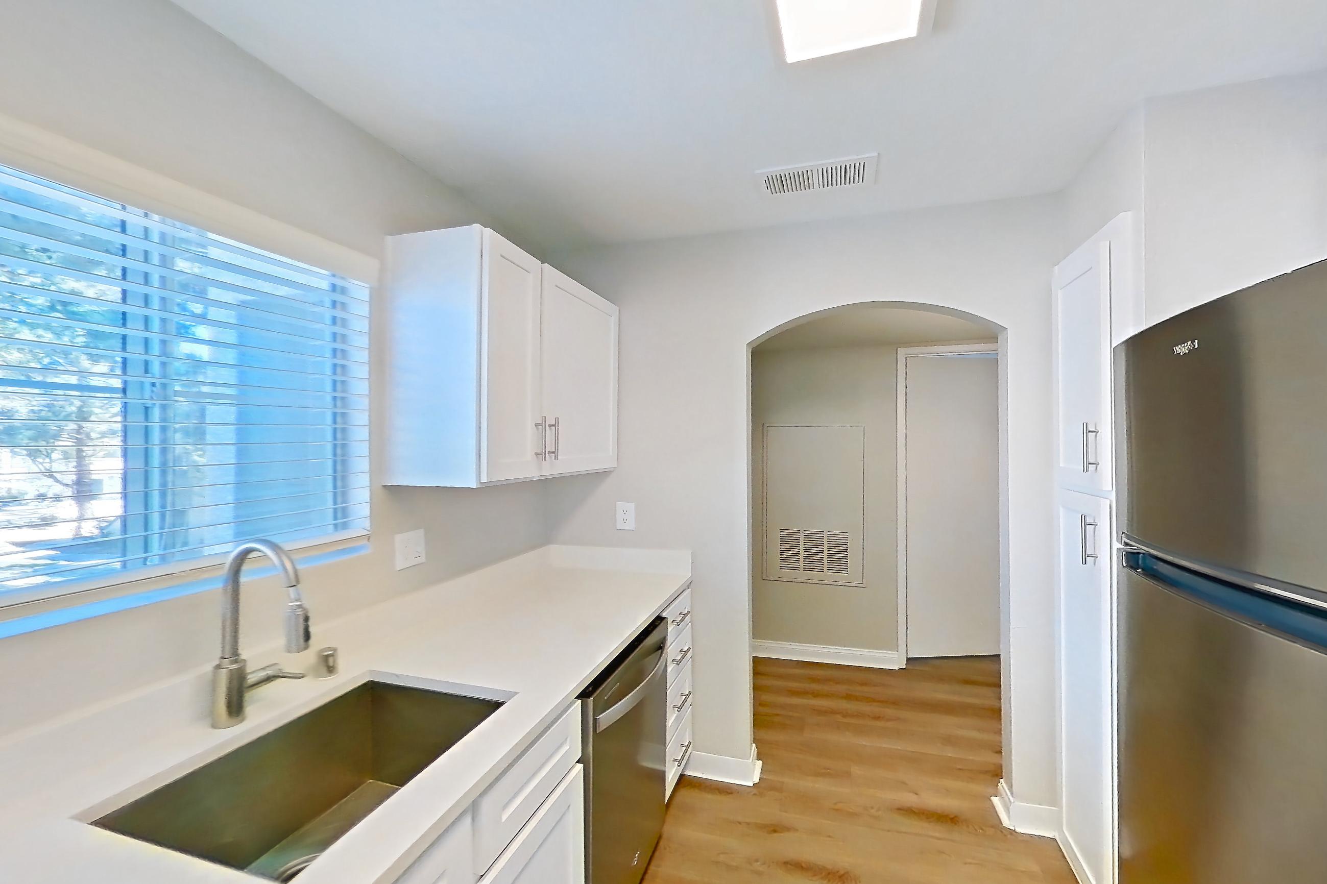 Kitchen with dishwasher, gas range, light countertops, light stone countertops, light wood-finish flooring, microwave, oven/range, refrigerator, and stainless steel appliances, Apartment 2020 at Vintage Pointe