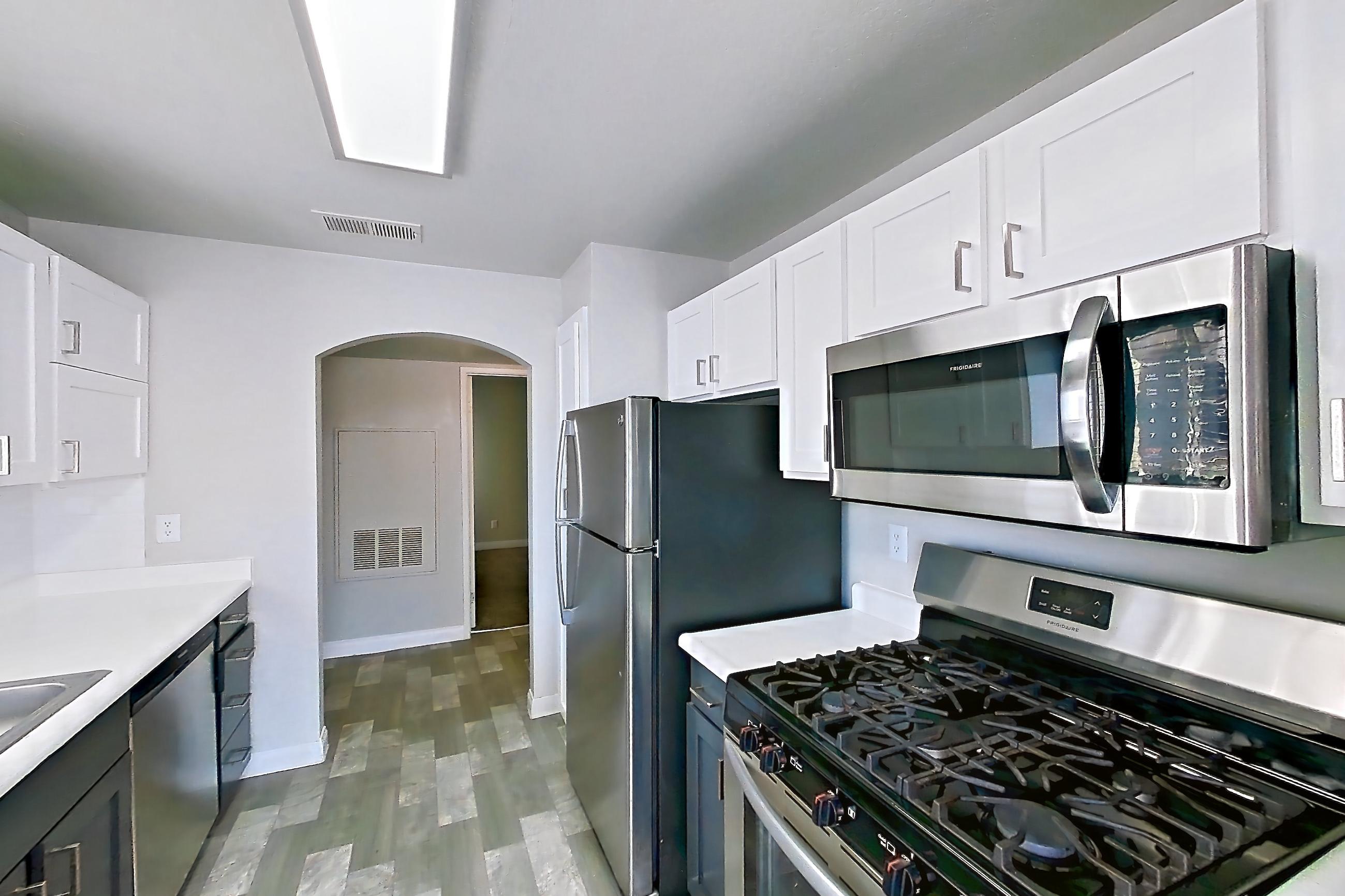 Kitchen with gas range, light countertops, light wood-finish flooring, microwave, oven/range, refrigerator, and stainless steel appliances, Apartment 2042 at Vintage Pointe