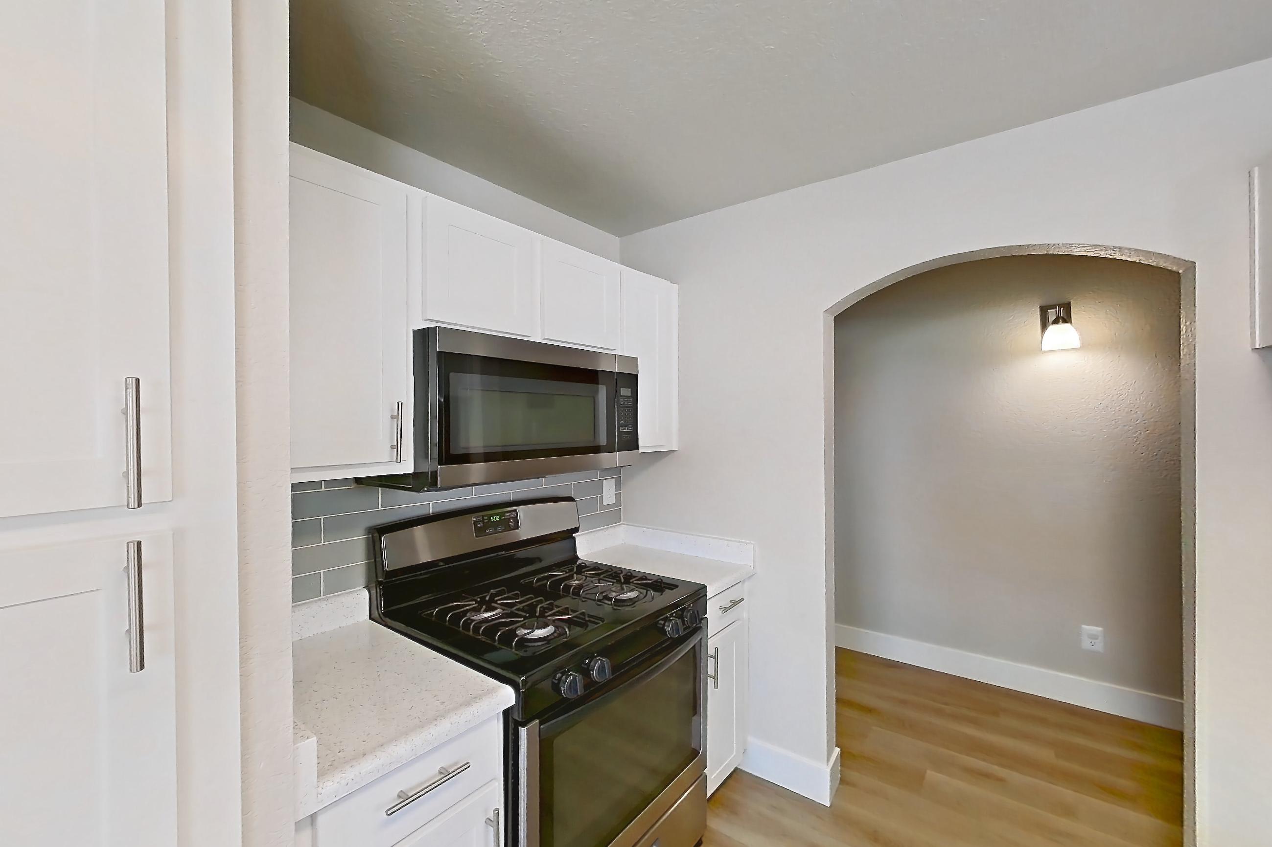 Kitchen with dishwasher, gas range, light countertops, light wood-finish flooring, microwave, oven/range, refrigerator, and stainless steel appliances, Apartment 2077 at Vintage Pointe