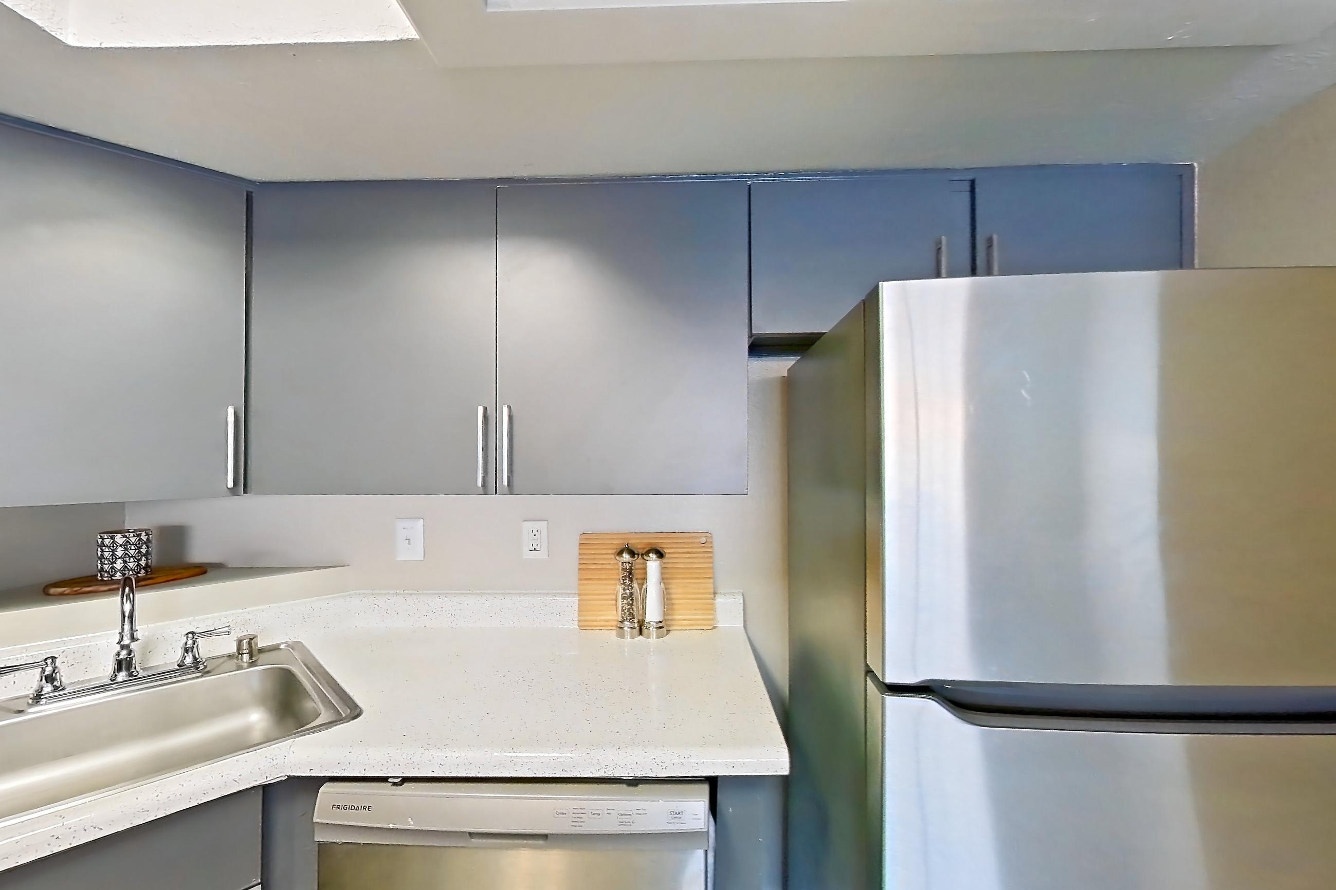 Kitchen with dishwasher, electric range, light stone countertops, light wood-finish flooring, oven/range, refrigerator, and stainless steel appliances, Apartment 1062 at The Met Las Vegas