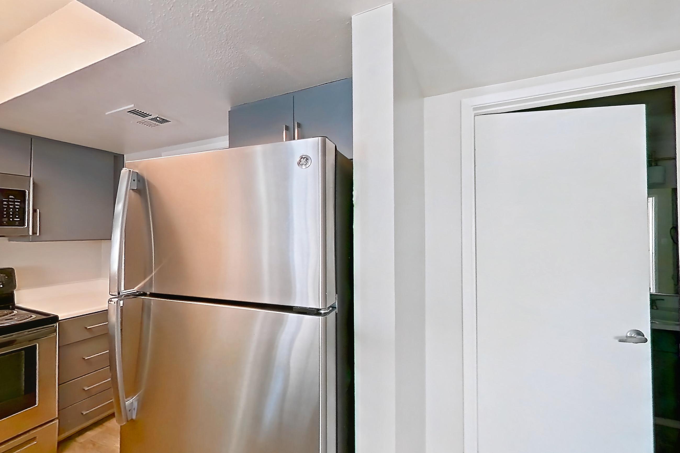 Kitchen with dishwasher, electric range, fireplace, light countertops, light stone countertops, light wood-finish flooring, microwave, oven/range, refrigerator, stainless steel appliances, and tile fireplace, Apartment 2233 at The Met Las Vegas