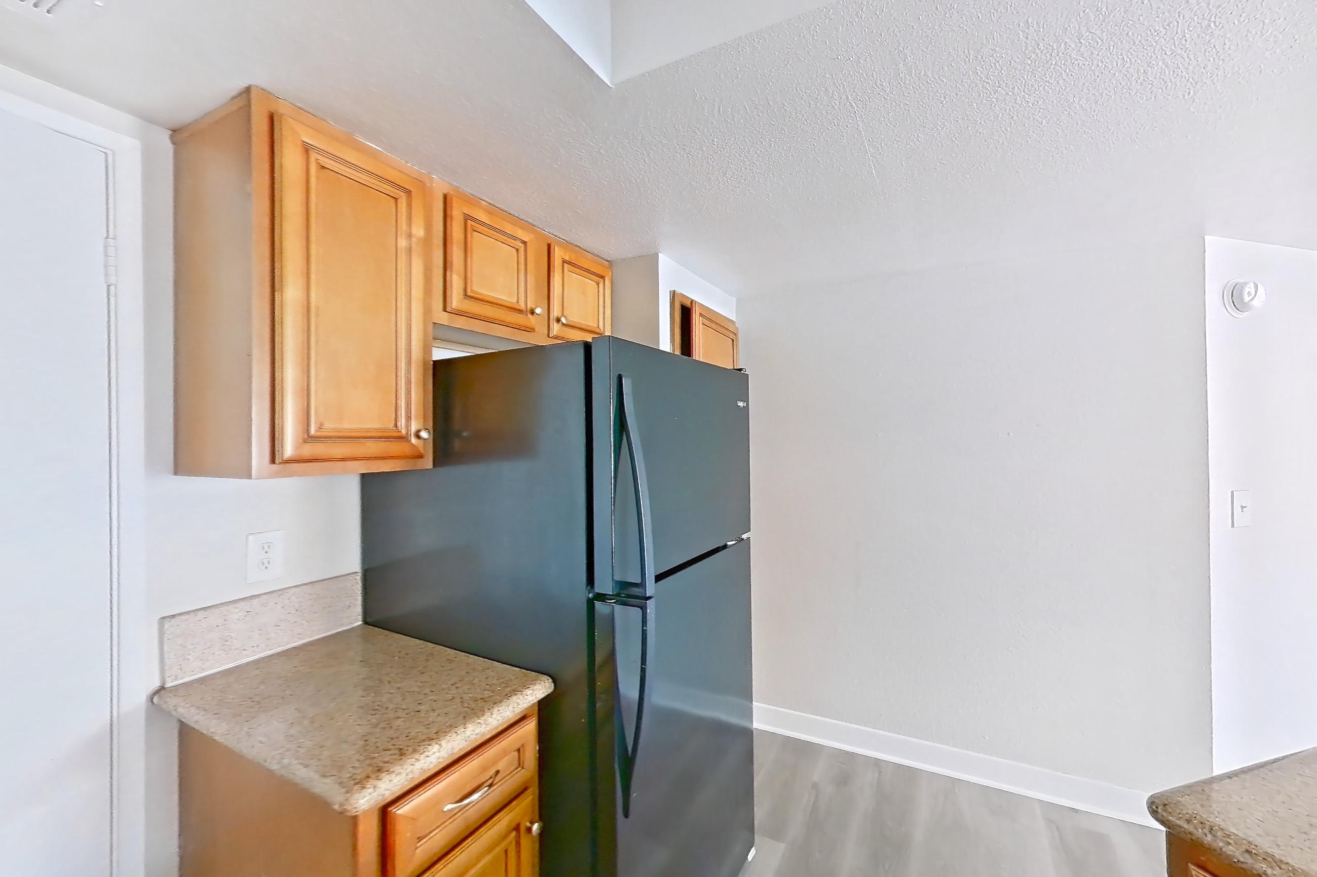 Kitchen with black appliances, dishwasher, electric range, light countertops, light stone countertops, light wood-finish flooring, microwave, oven/range, and refrigerator, Apartment 2171 at The Met Las Vegas