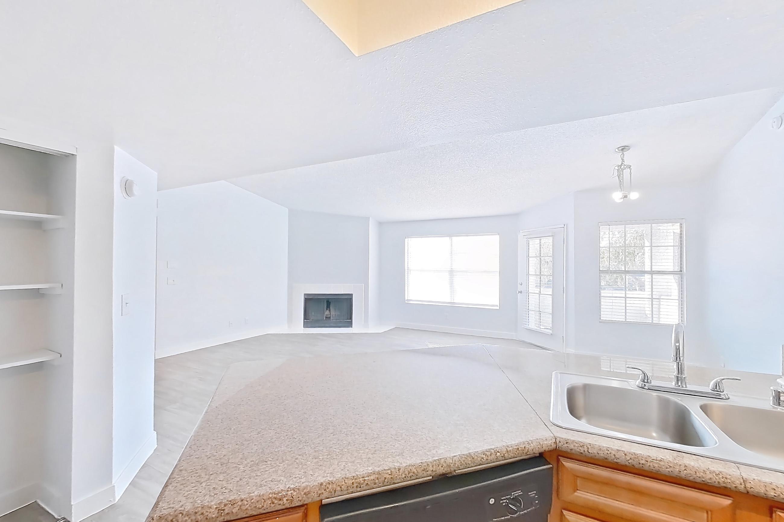 Kitchen with black appliances, dishwasher, electric range, fireplace, light countertops, light stone countertops, light wood-finish flooring, oven/range, and refrigerator, Apartment 2175 at The Met Las Vegas