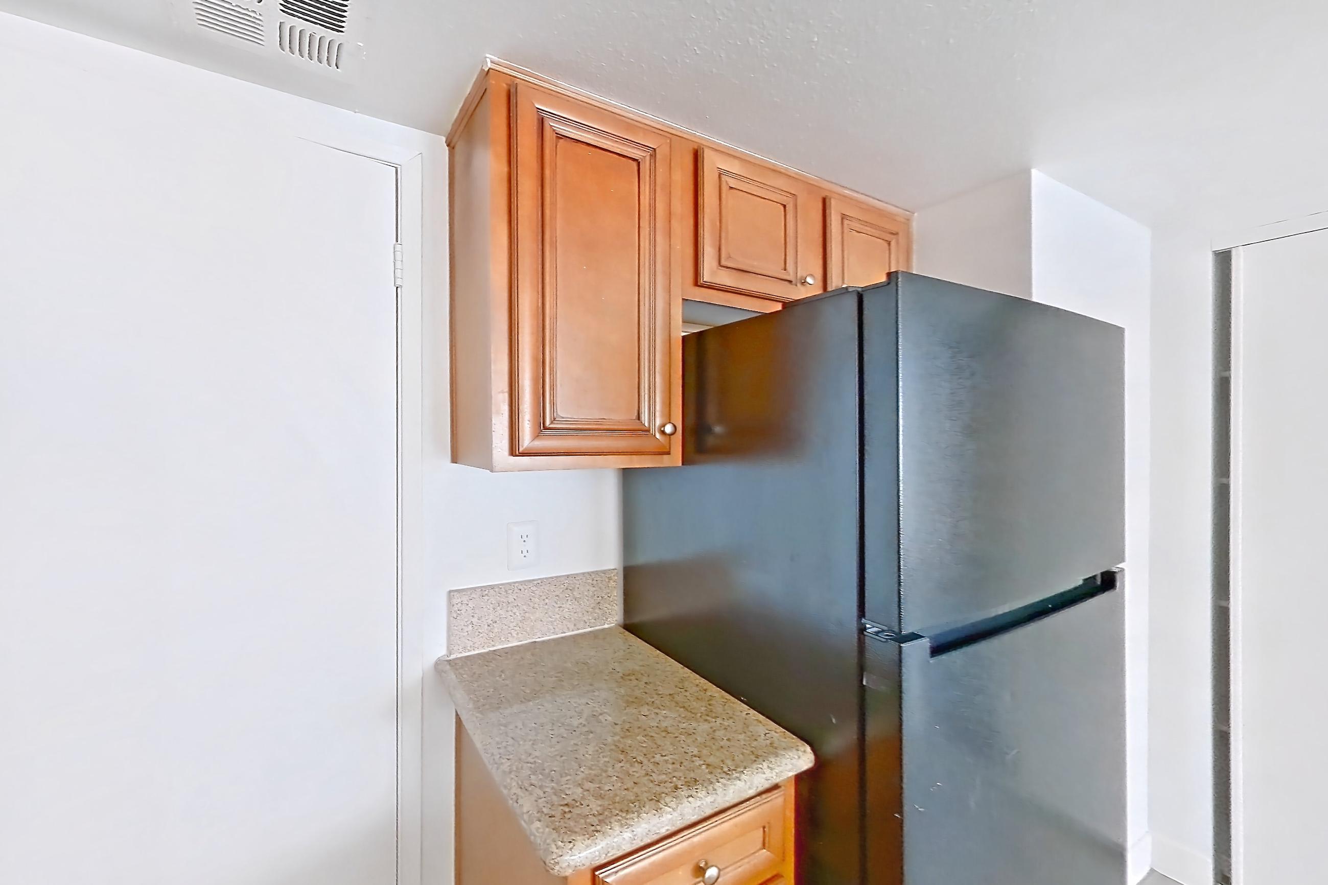 Kitchen with black appliances, dishwasher, electric range, fireplace, light countertops, light stone countertops, light wood-finish flooring, oven/range, and refrigerator, Apartment 2175 at The Met Las Vegas