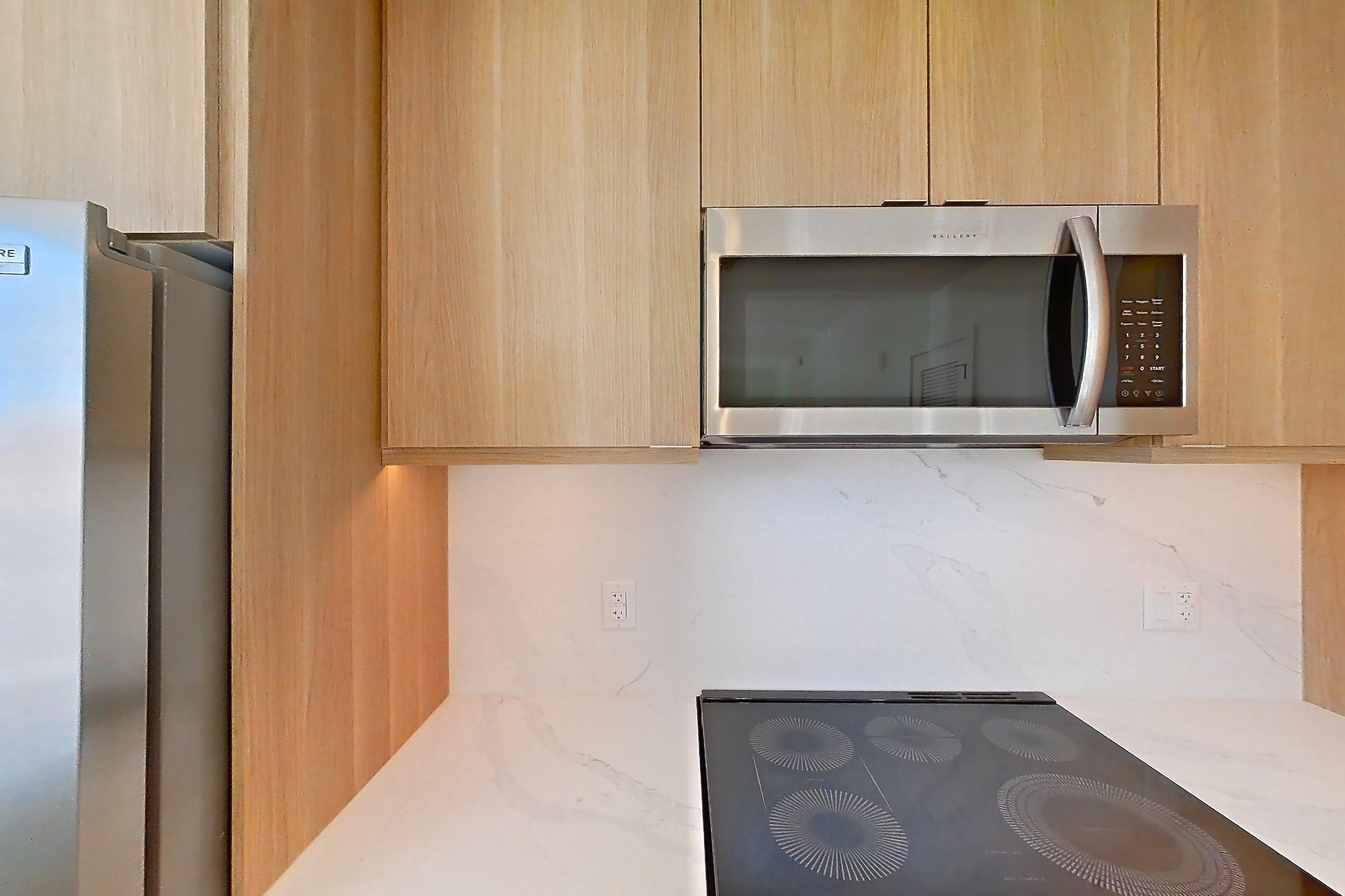 Kitchen with electric range, light stone countertops, light wood-finish flooring, oven/range, refrigerator, and stainless steel appliances, Apartment 112 at Residences at Mazza