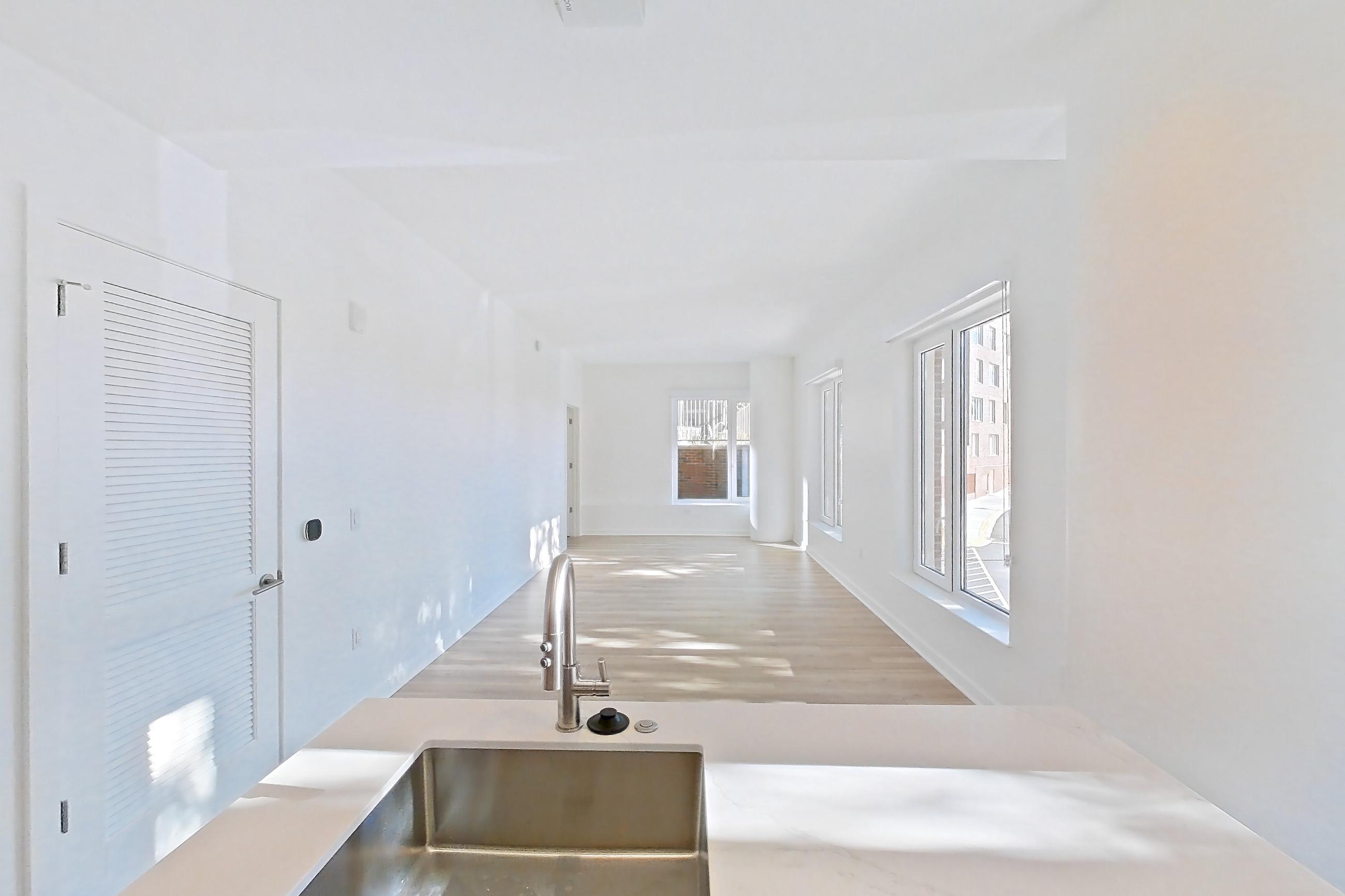 Kitchen with electric range, light stone countertops, light wood-finish flooring, oven/range, refrigerator, and stainless steel appliances, Apartment 112 at Residences at Mazza