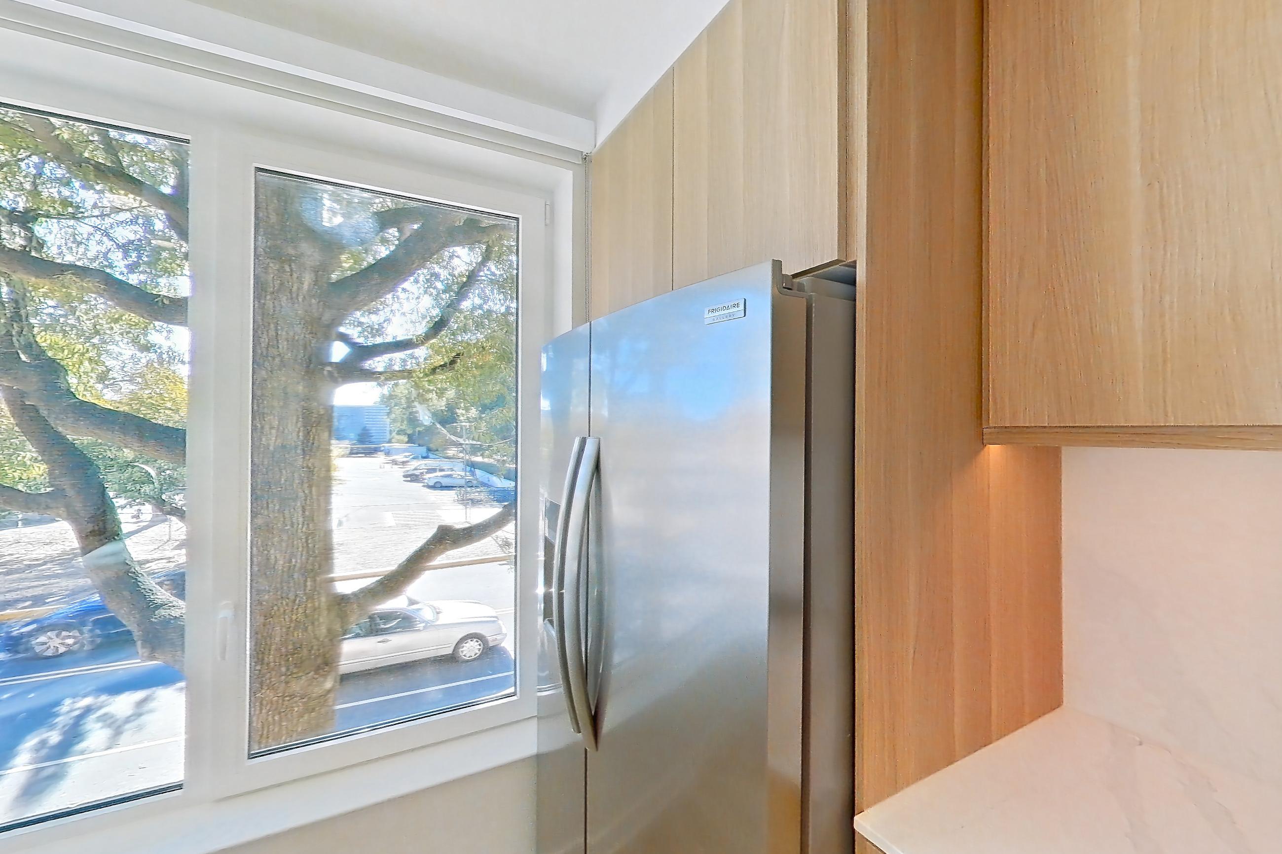 Kitchen with electric range, light stone countertops, light wood-finish flooring, oven/range, refrigerator, and stainless steel appliances, Apartment 112 at Residences at Mazza