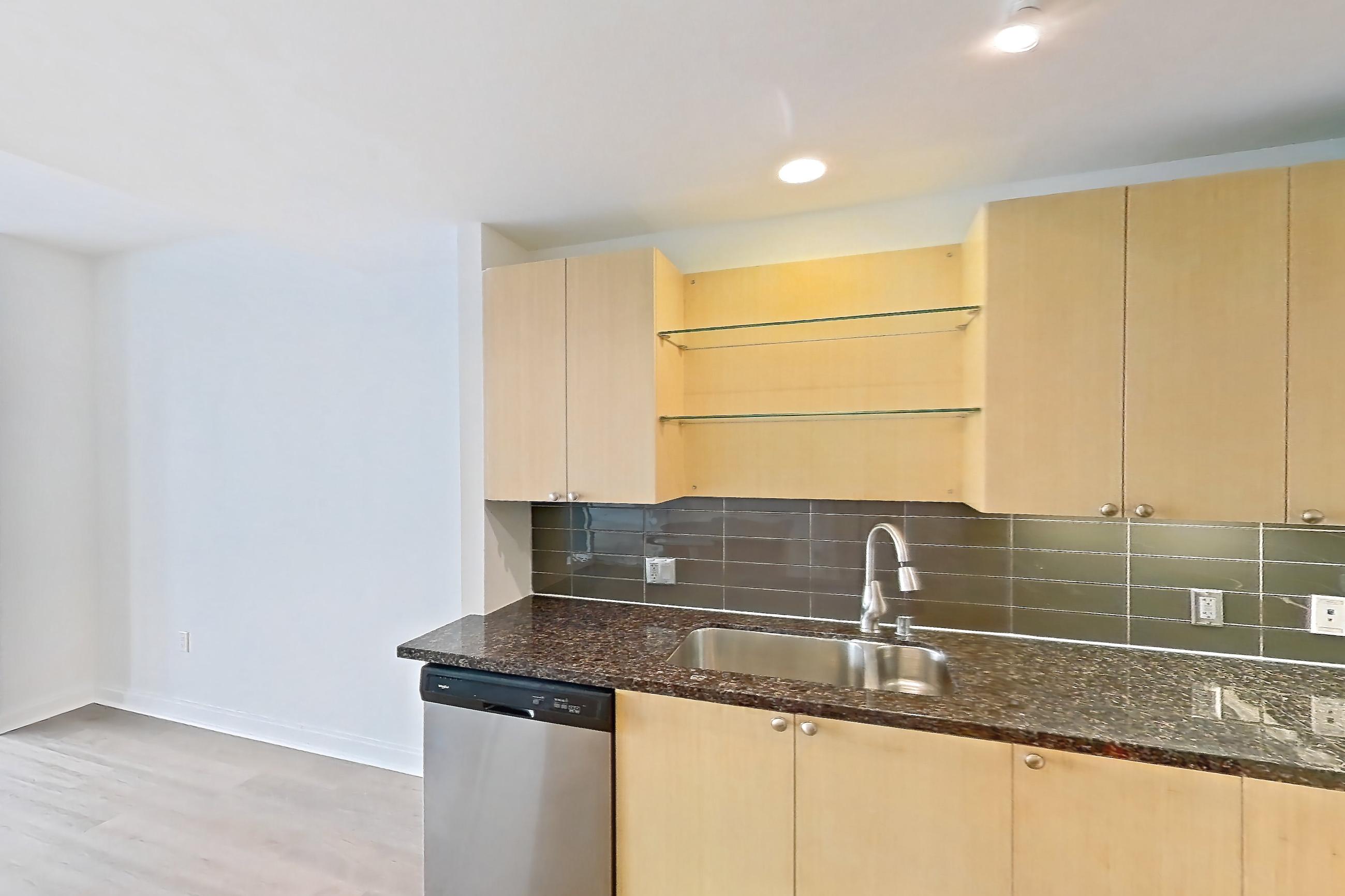 Kitchen with dark stone countertops, dishwasher, electric range, light wood-finish flooring, oven/range, and stainless steel appliances, Apartment E-0353 at The Element