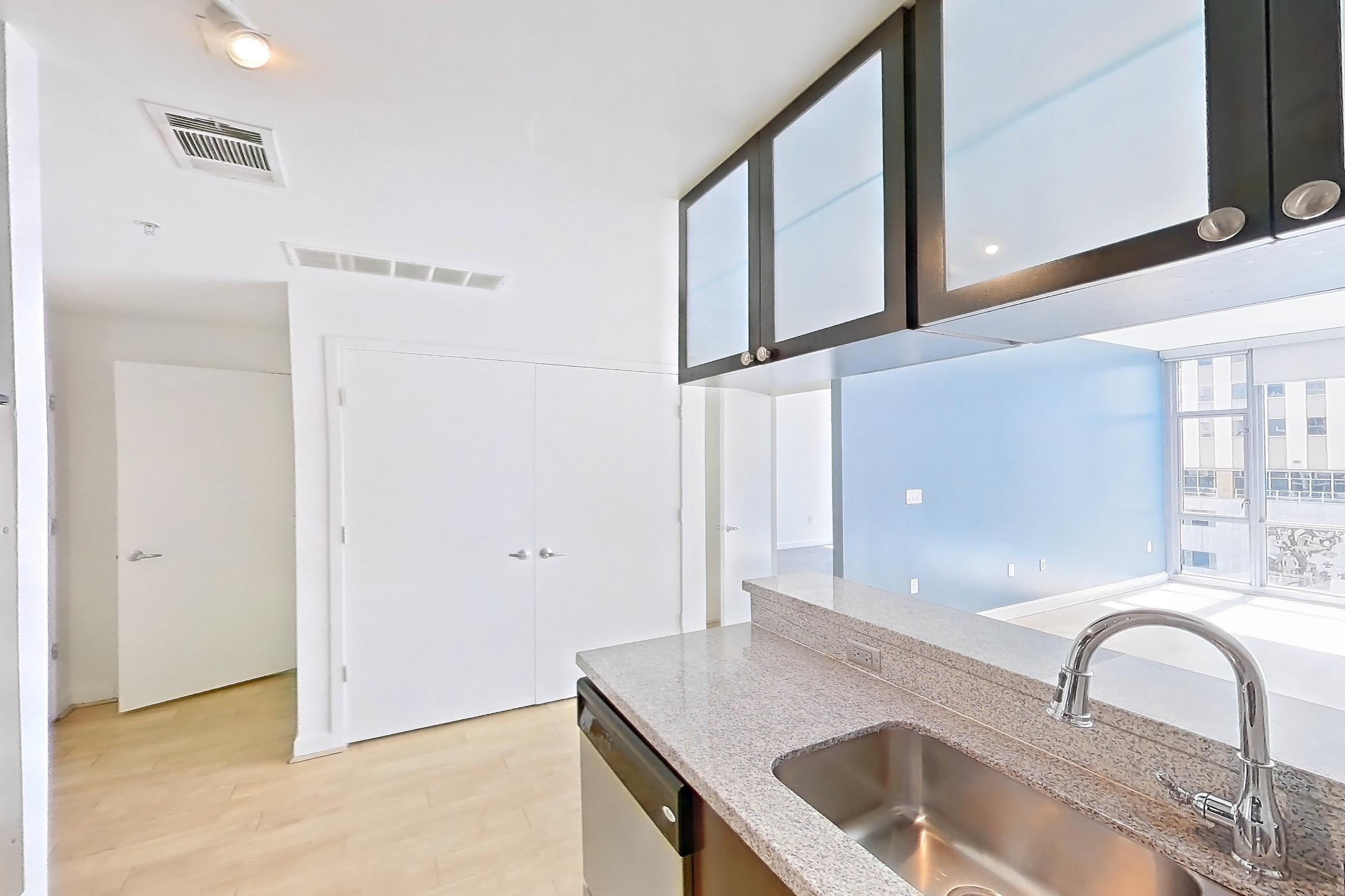 Kitchen with dishwasher, light stone countertops, light wood-finish flooring, oven/range, refrigerator, and stainless steel appliances, Apartment E-0559 at The Element