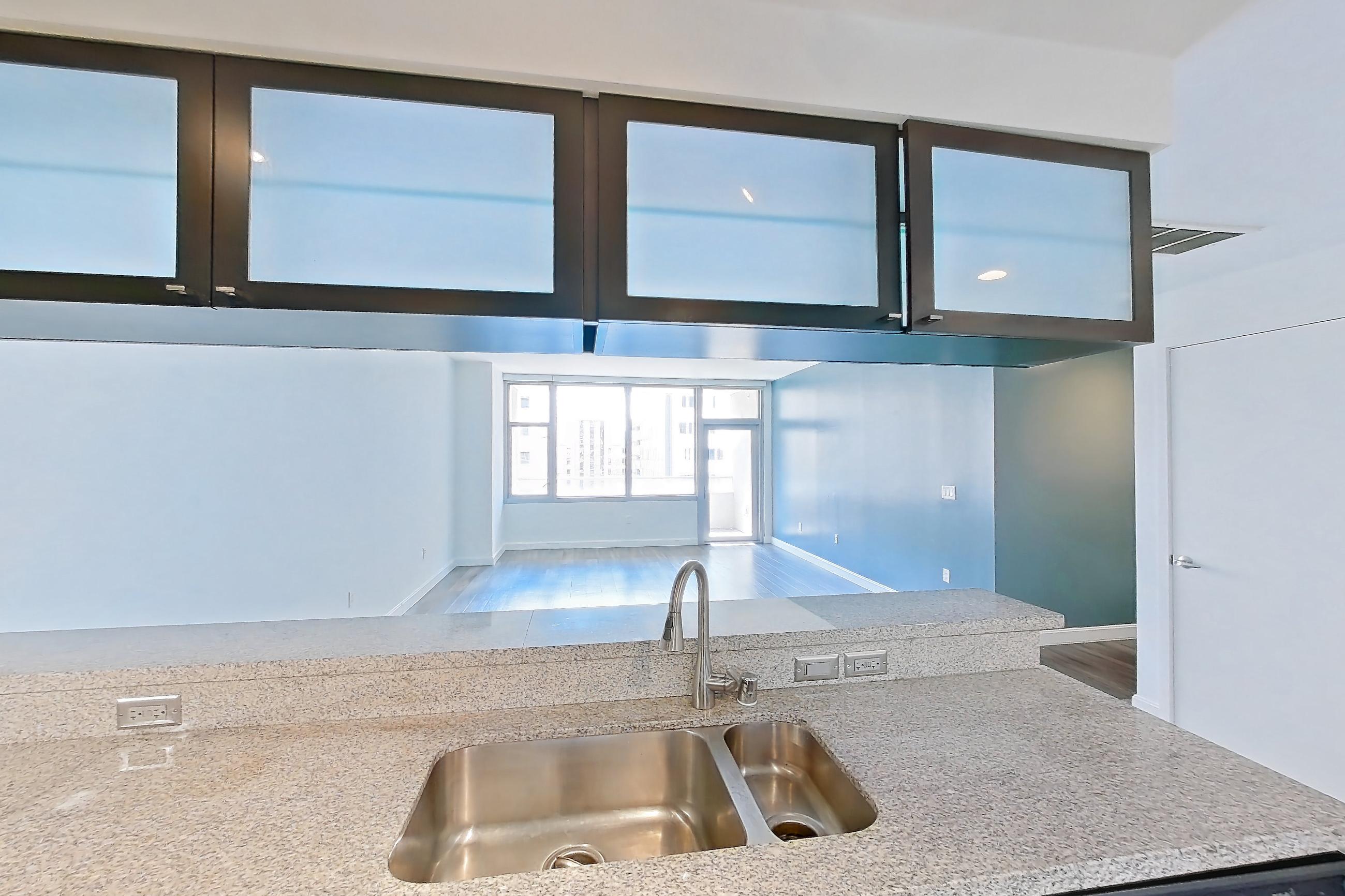 Kitchen with dark wood-finish flooring, dishwasher, electric range, light stone countertops, light wood-finish flooring, microwave, oven/range, refrigerator, and stainless steel appliances, Apartment E-0660 at The Element