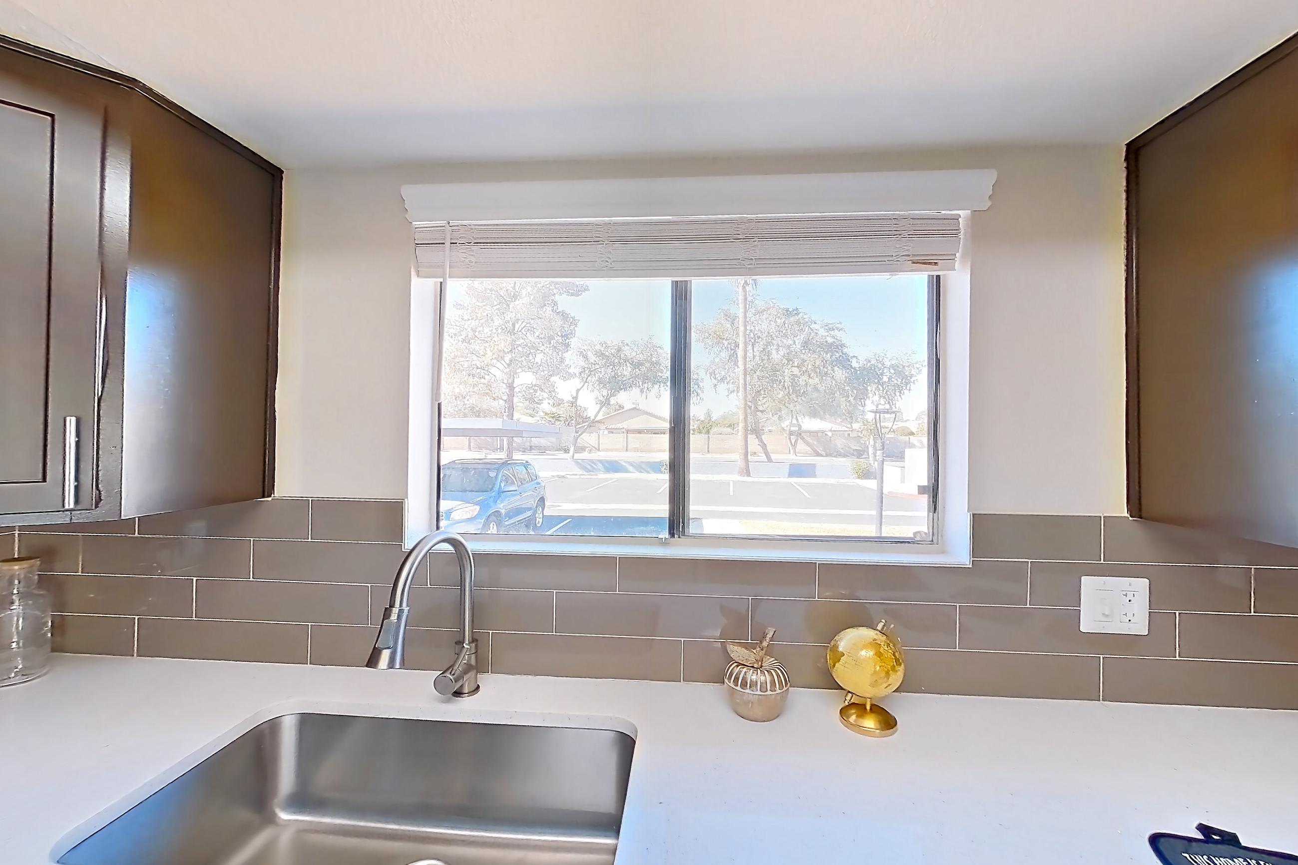 Kitchen with black appliances, dishwasher, electric range, light stone countertops, light wood-finish flooring, oven/range, range hood, and refrigerator, Apartment A-1102 at Arches at Hidden Creek