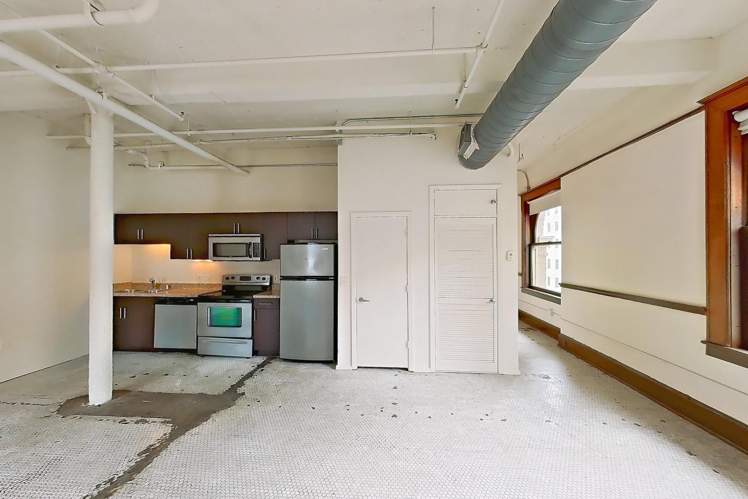 Living room with dishwasher, electric range, light countertops, oven/range, refrigerator, stainless steel appliances, and white appliances, Apartment W-0702 at The Wilson