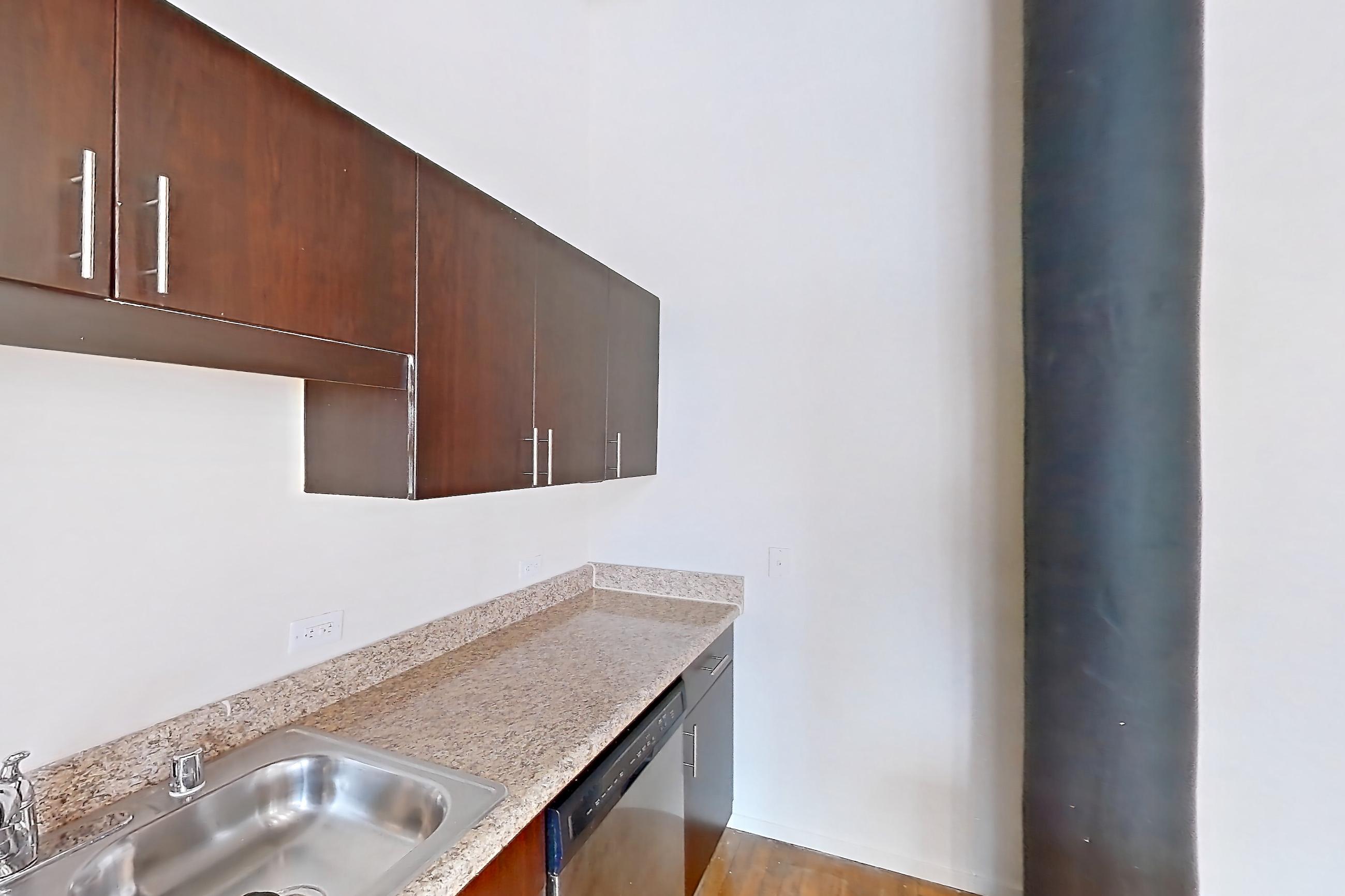 Kitchen with dishwasher, electric range, light stone countertops, light wood-finish flooring, microwave, oven/range, refrigerator, stainless steel appliances, white appliances, and wood-finish flooring, Apartment W-0206 at The Wilson