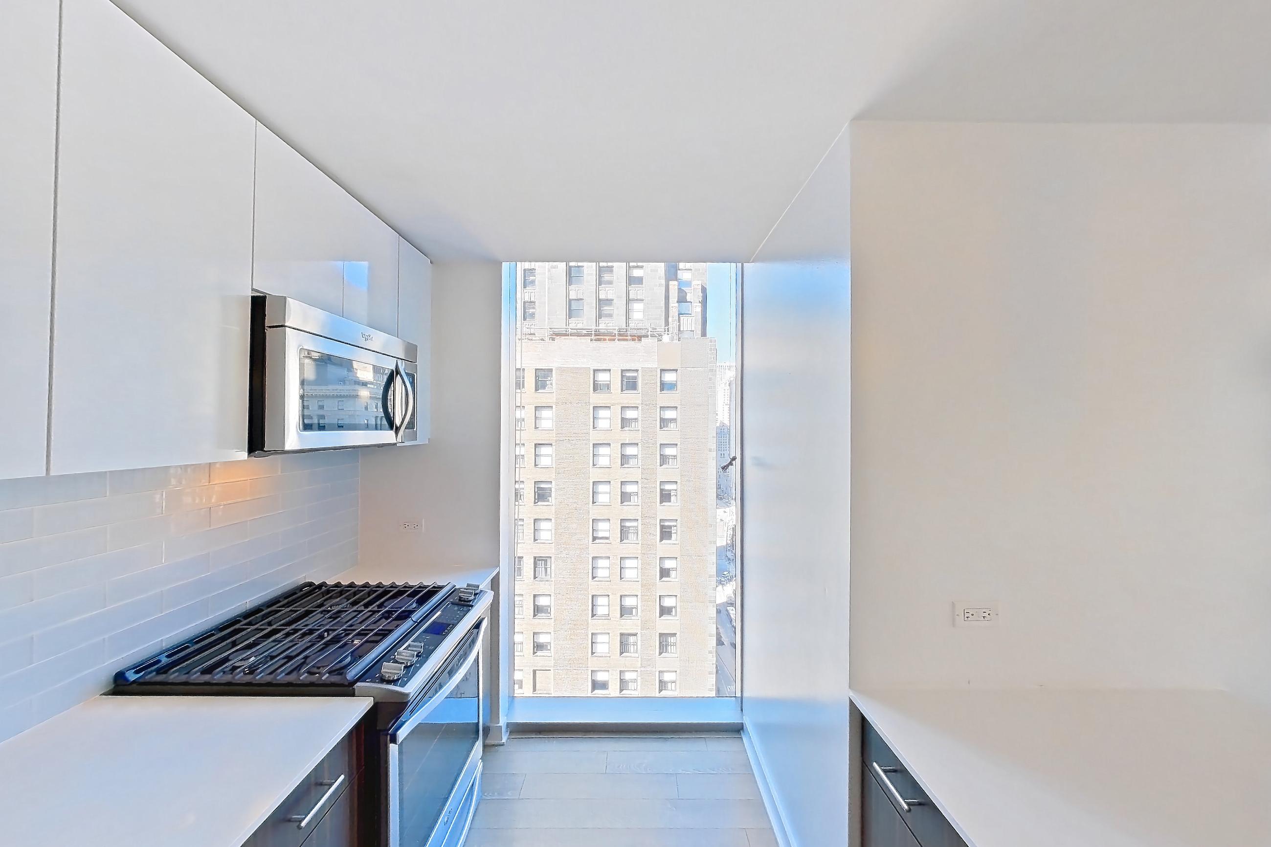 Kitchen with gas range, light countertops, light wood-finish flooring, microwave, oven/range, and stainless steel appliances, Apartment 2504 at Mila