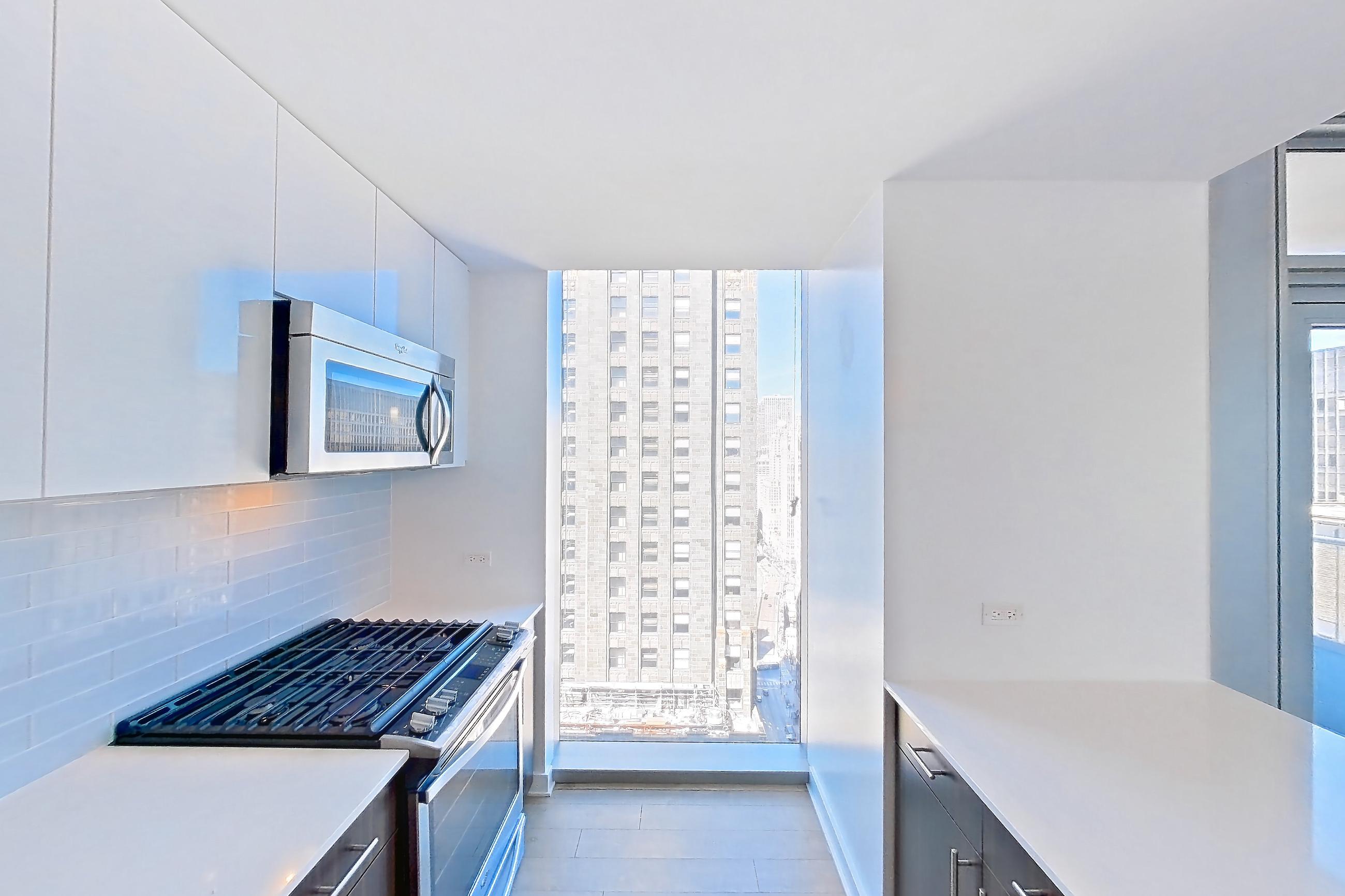 Kitchen with gas range, light countertops, light stone countertops, light wood-finish flooring, oven/range, and stainless steel appliances, Apartment 3604 at Mila