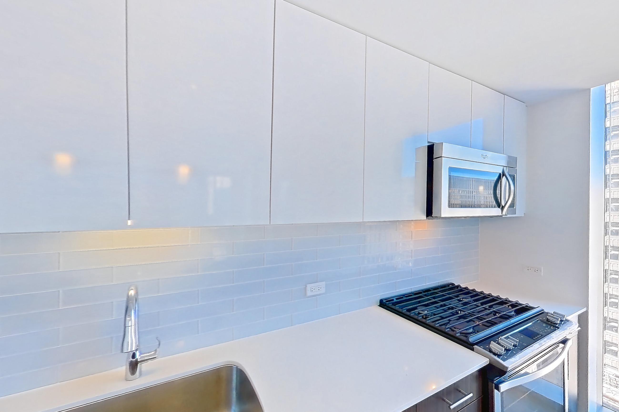 Kitchen with gas range, light countertops, light stone countertops, light wood-finish flooring, oven/range, and stainless steel appliances, Apartment 3604 at Mila