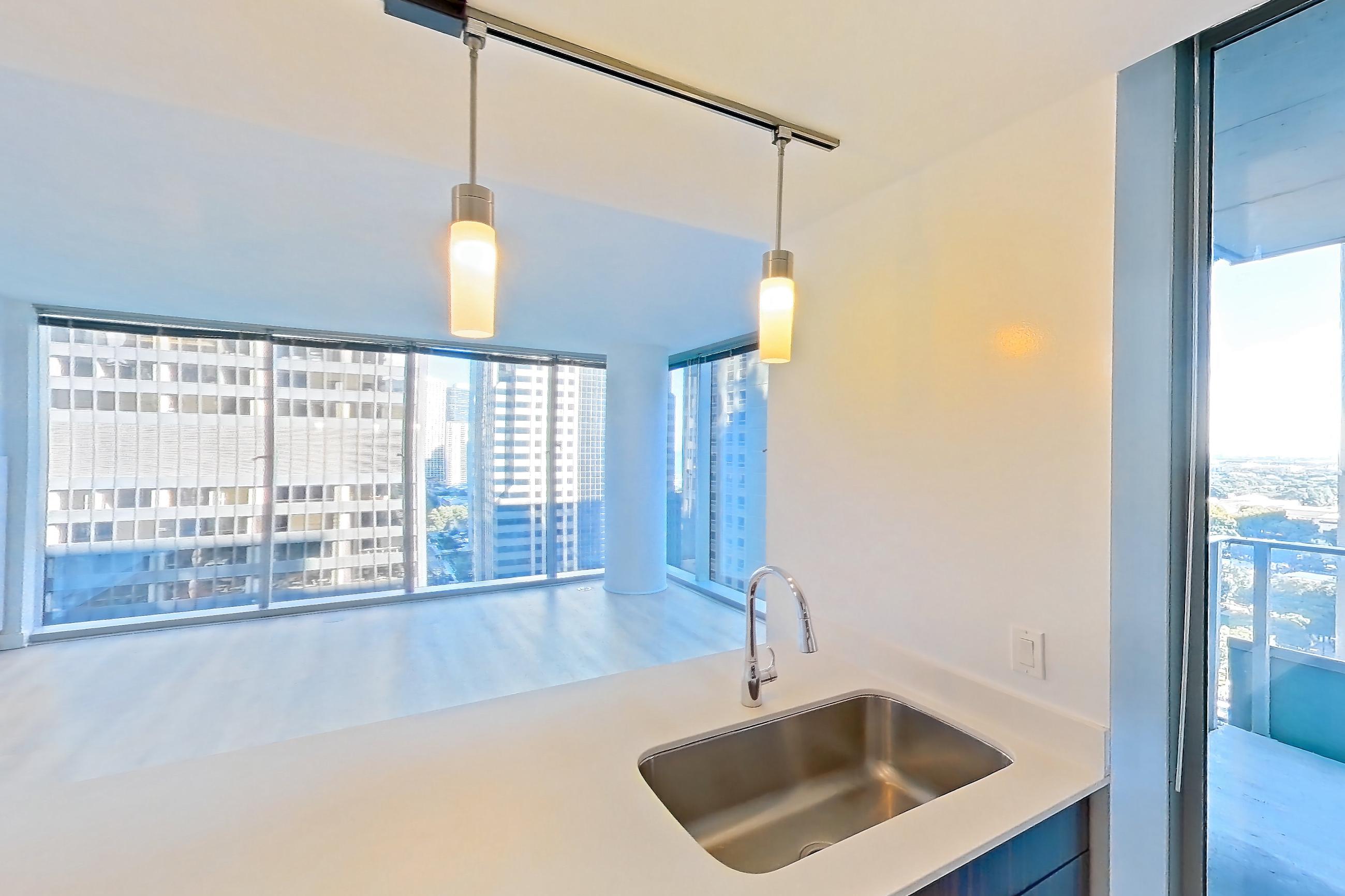 Kitchen with dishwasher, gas range, light countertops, light stone countertops, light wood-finish flooring, microwave, oven/range, refrigerator, and stainless steel appliances, Apartment 2207 at Mila