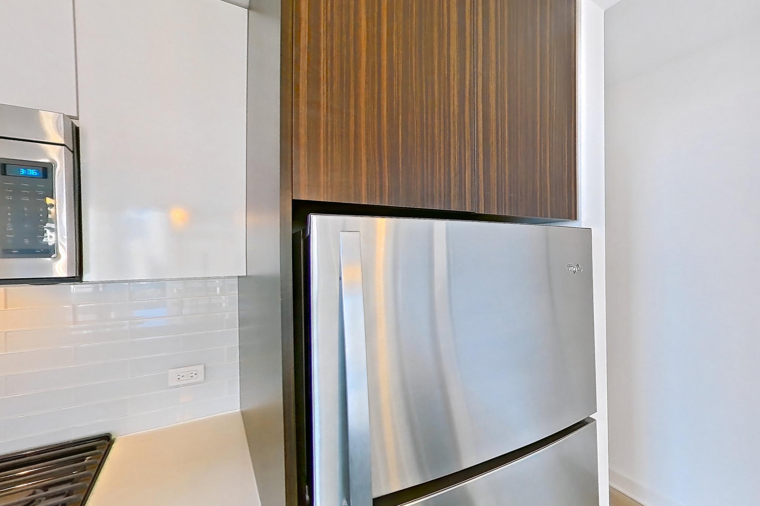 Kitchen with dishwasher, gas range, light countertops, light stone countertops, light wood-finish flooring, microwave, oven/range, refrigerator, and stainless steel appliances, Apartment 2207 at Mila