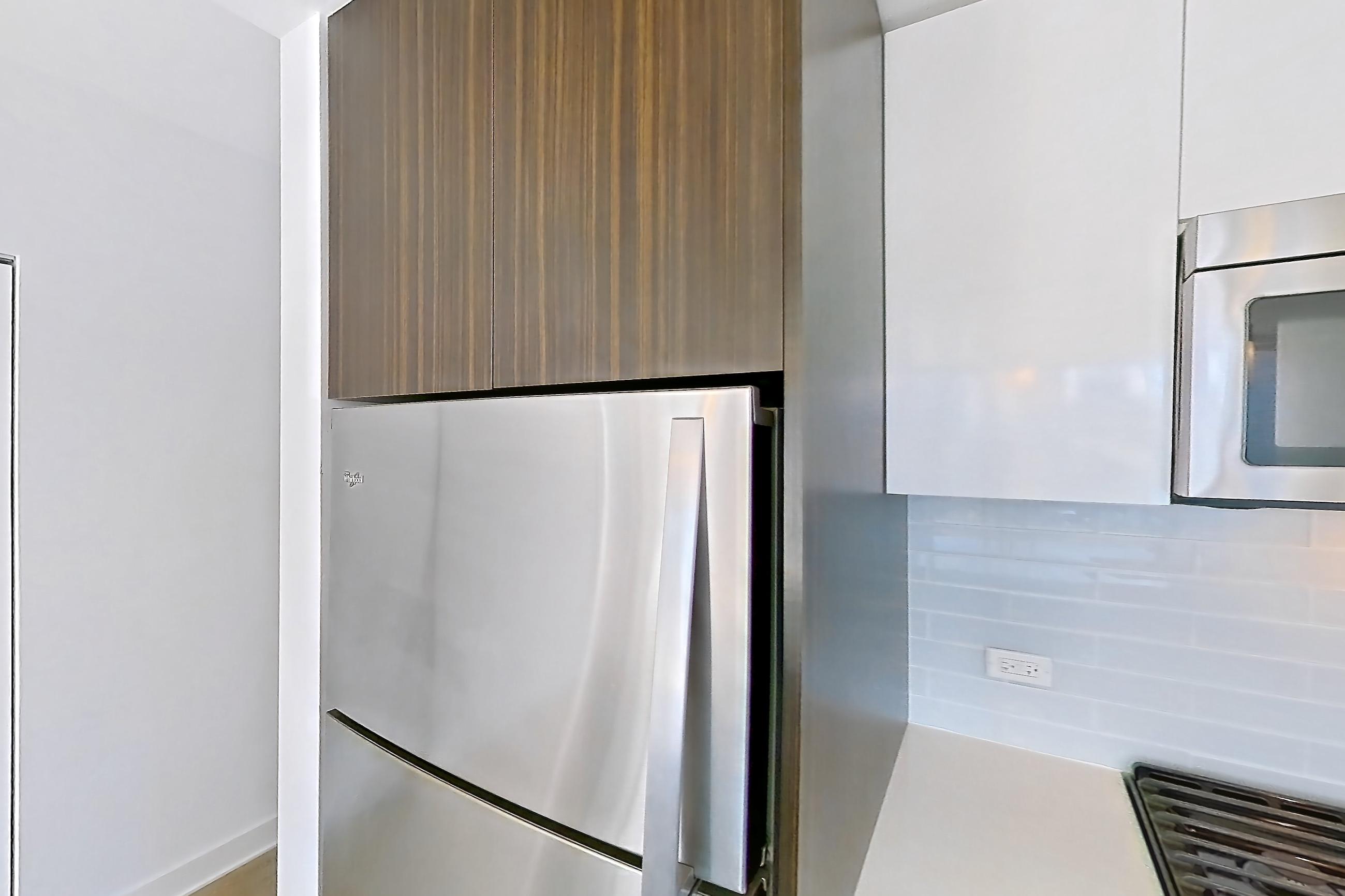 Kitchen with dishwasher, gas range, light countertops, light stone countertops, light wood-finish flooring, microwave, oven/range, refrigerator, skyline view, and stainless steel appliances, Apartment 2810 at Mila