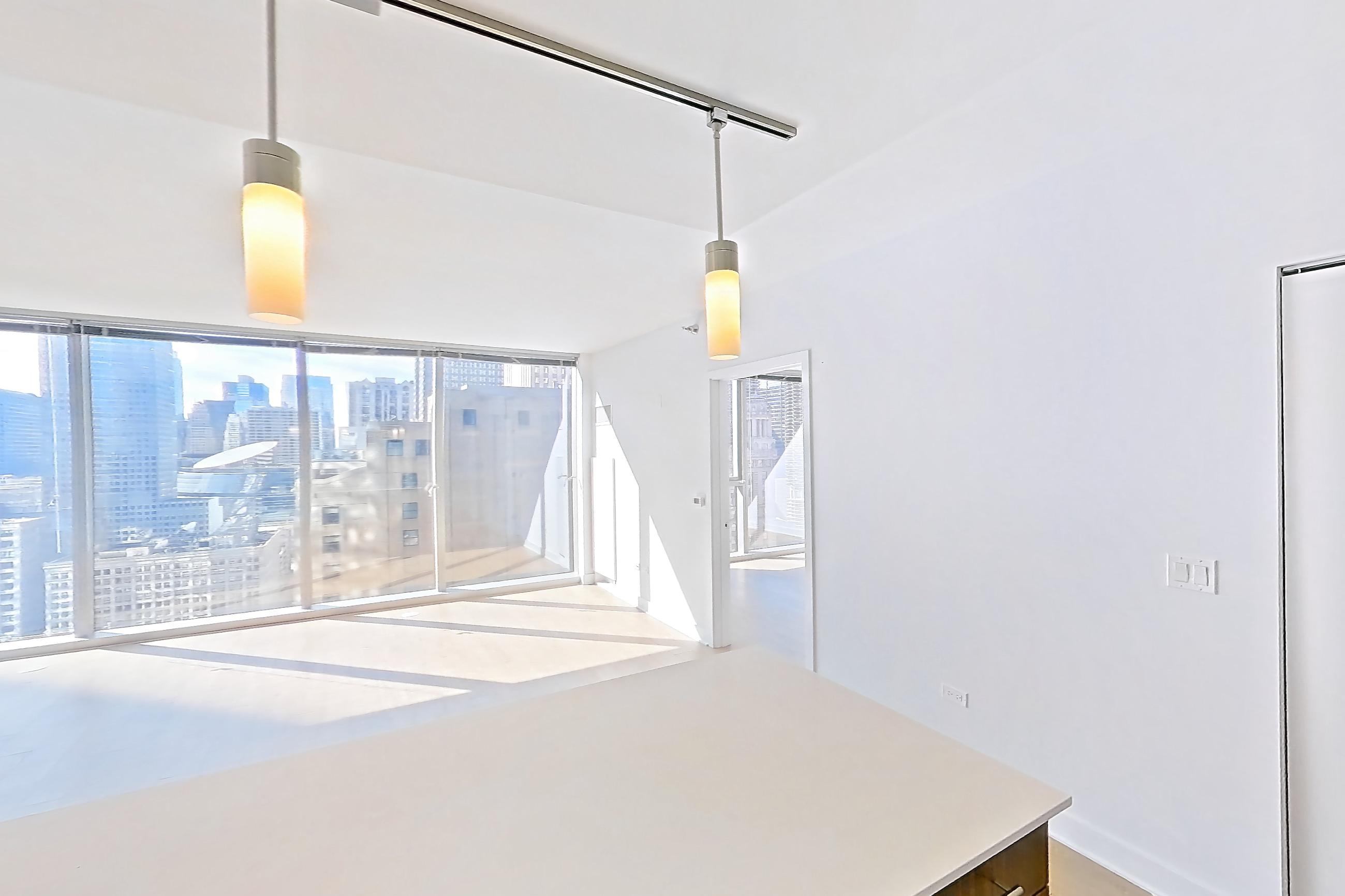 Kitchen with dishwasher, gas range, light countertops, light stone countertops, light wood-finish flooring, microwave, oven/range, refrigerator, skyline view, and stainless steel appliances, Apartment 2810 at Mila