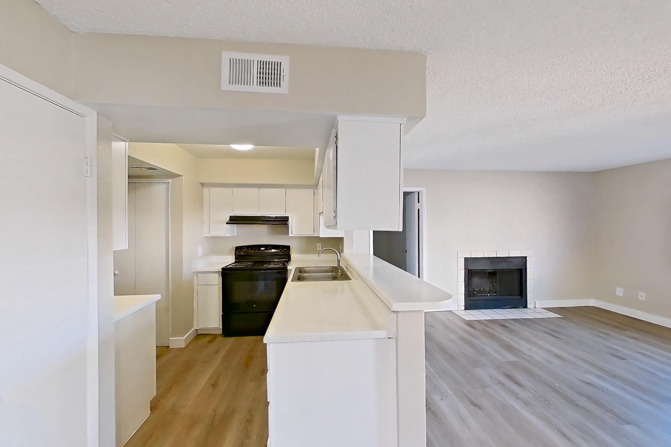 Dining room with black appliances, electric range, fireplace, light countertops, light wood-finish flooring, oven/range, and tile fireplace, Apartment 2079 at Terra Vida Apartments