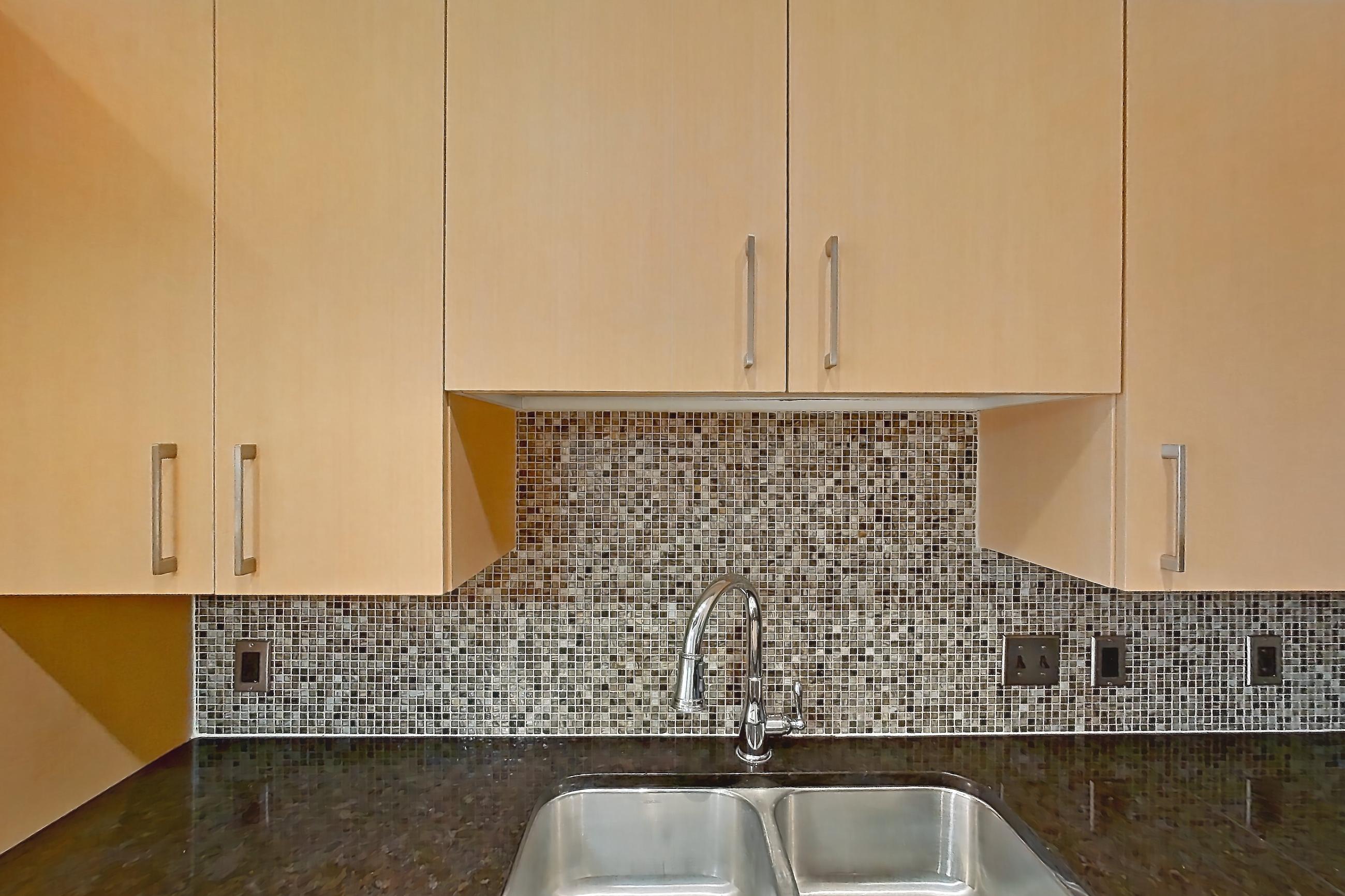 Kitchen with dark stone countertops, dishwasher, electric range, light countertops, light wood-finish flooring, microwave, oven/range, refrigerator, stainless steel appliances, and white appliances, Apartment C-0611 at The Continental