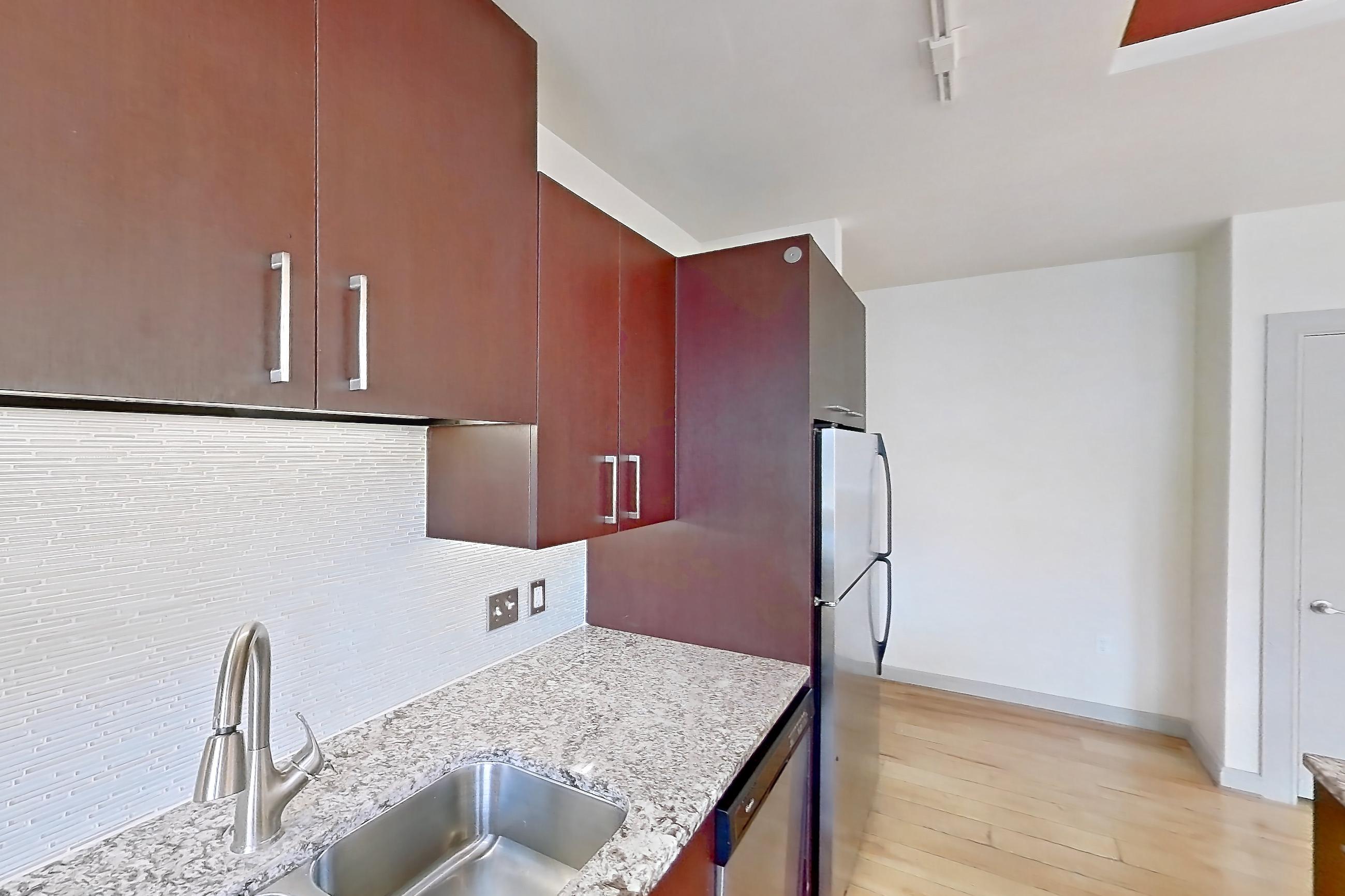 Kitchen with dishwasher, electric range, light stone countertops, light wood-finish flooring, oven/range, refrigerator, and stainless steel appliances, Apartment C-0315 at The Continental