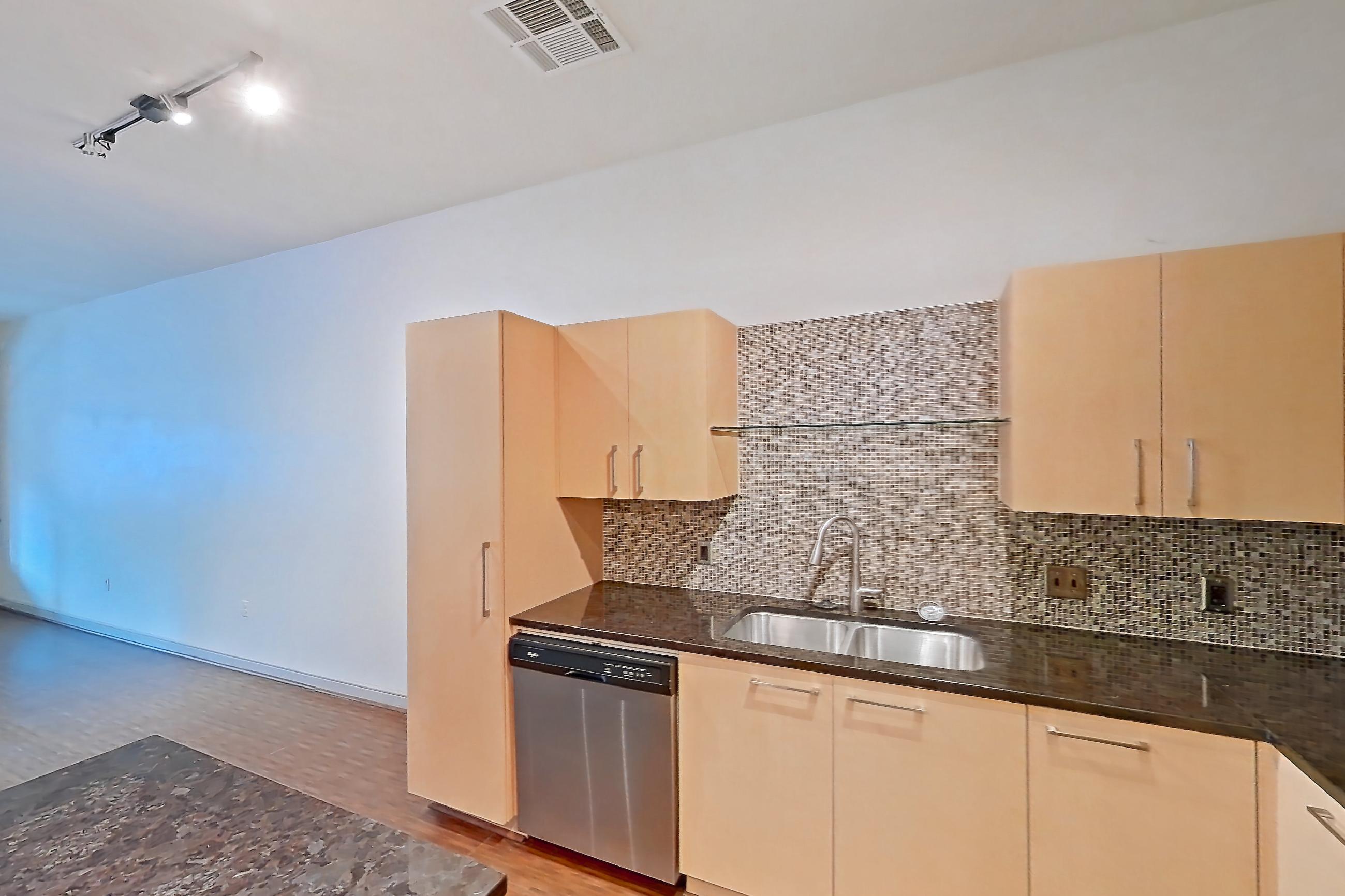 Kitchen with dark stone countertops, dishwasher, electric range, light wood-finish flooring, microwave, oven/range, refrigerator, and stainless steel appliances, Apartment C-0214 at The Continental