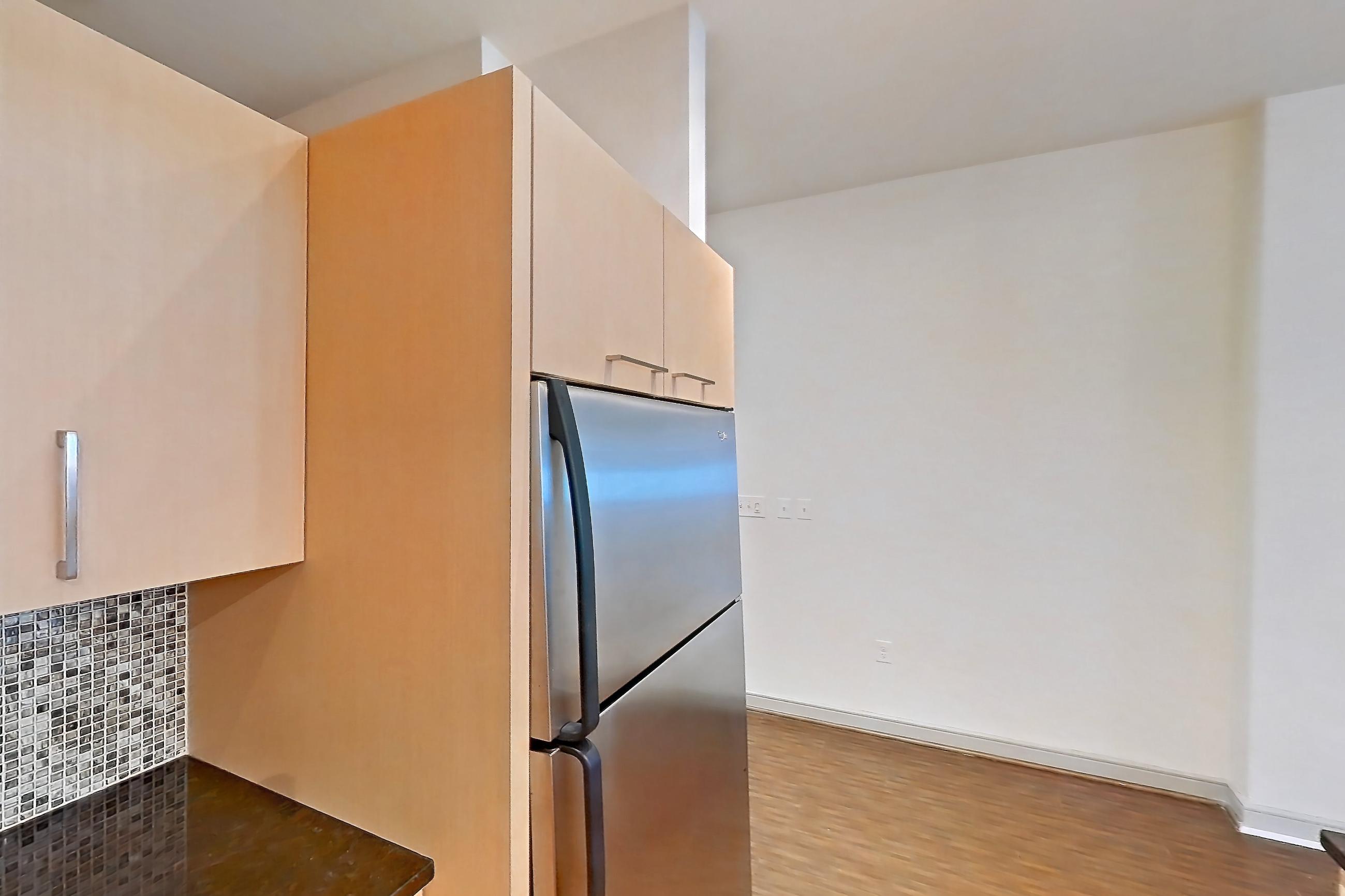 Kitchen with dark stone countertops, dishwasher, electric range, light wood-finish flooring, microwave, oven/range, refrigerator, and stainless steel appliances, Apartment C-0214 at The Continental