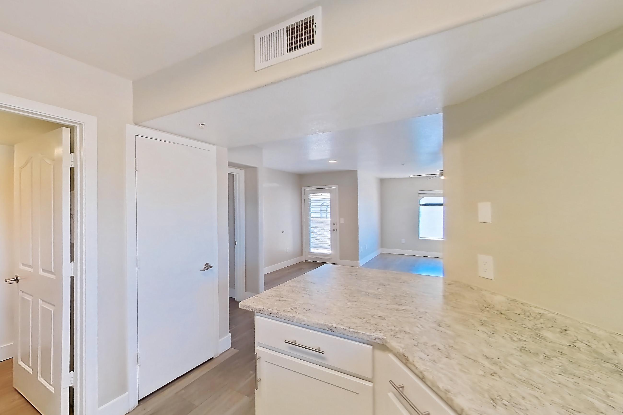 Kitchen with dishwasher, electric range, light countertops, light stone countertops, light wood-finish flooring, microwave, oven/range, refrigerator, and stainless steel appliances, Apartment 3184 at San Valiente