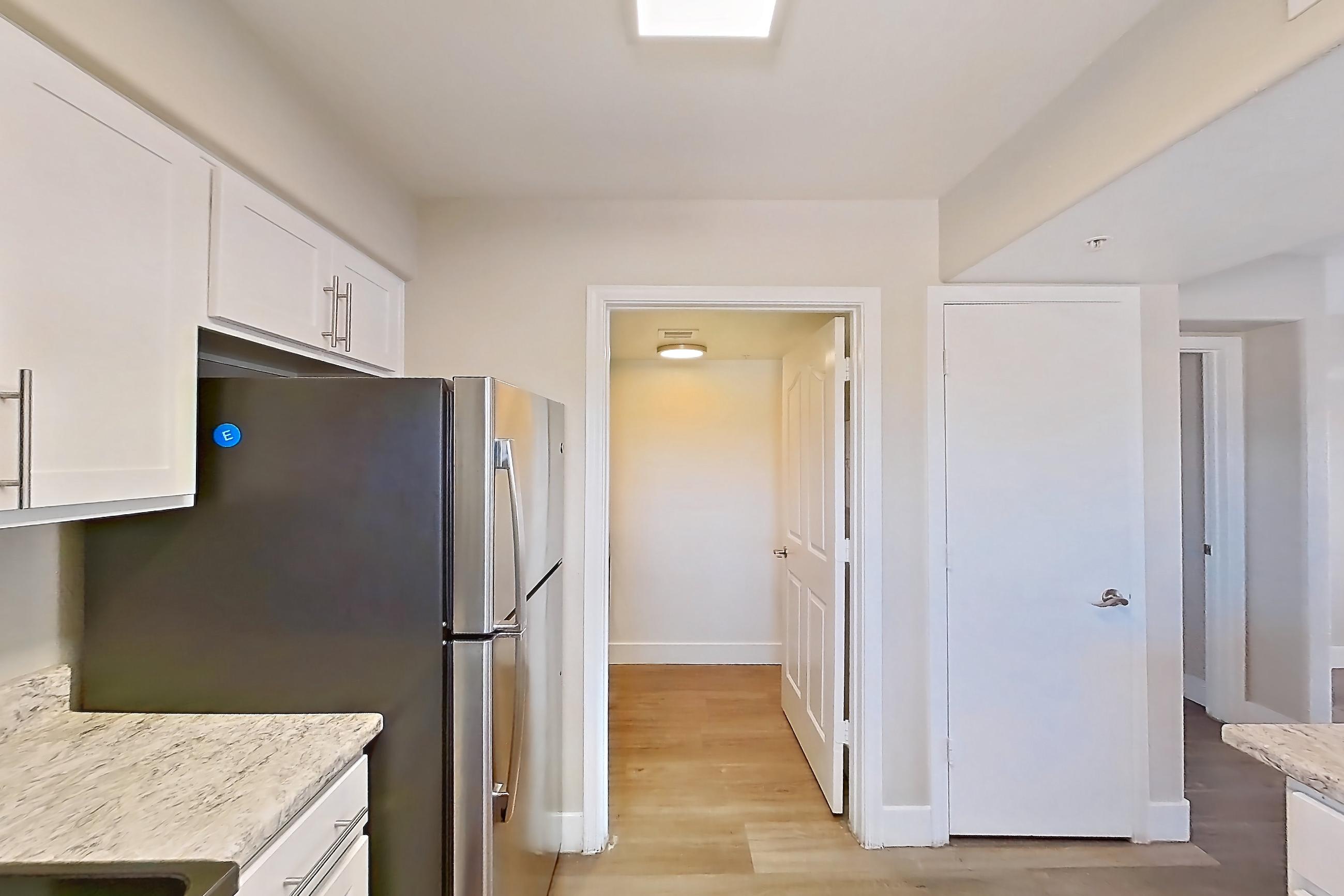 Kitchen with dishwasher, electric range, light countertops, light stone countertops, light wood-finish flooring, microwave, oven/range, refrigerator, and stainless steel appliances, Apartment 3184 at San Valiente