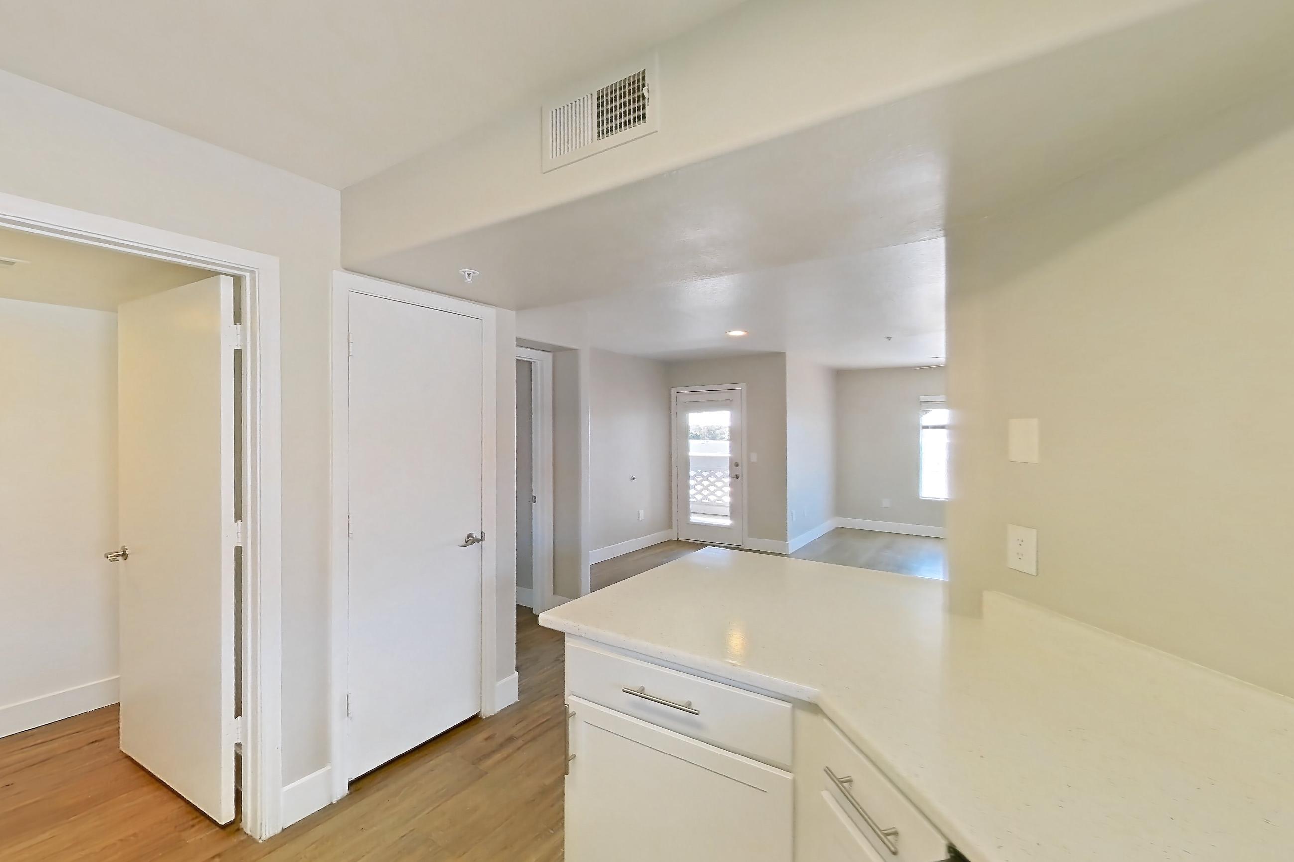 Kitchen with dishwasher, electric range, light countertops, light stone countertops, light wood-finish flooring, microwave, oven/range, refrigerator, stainless steel appliances, and white appliances, Apartment 3190 at San Valiente