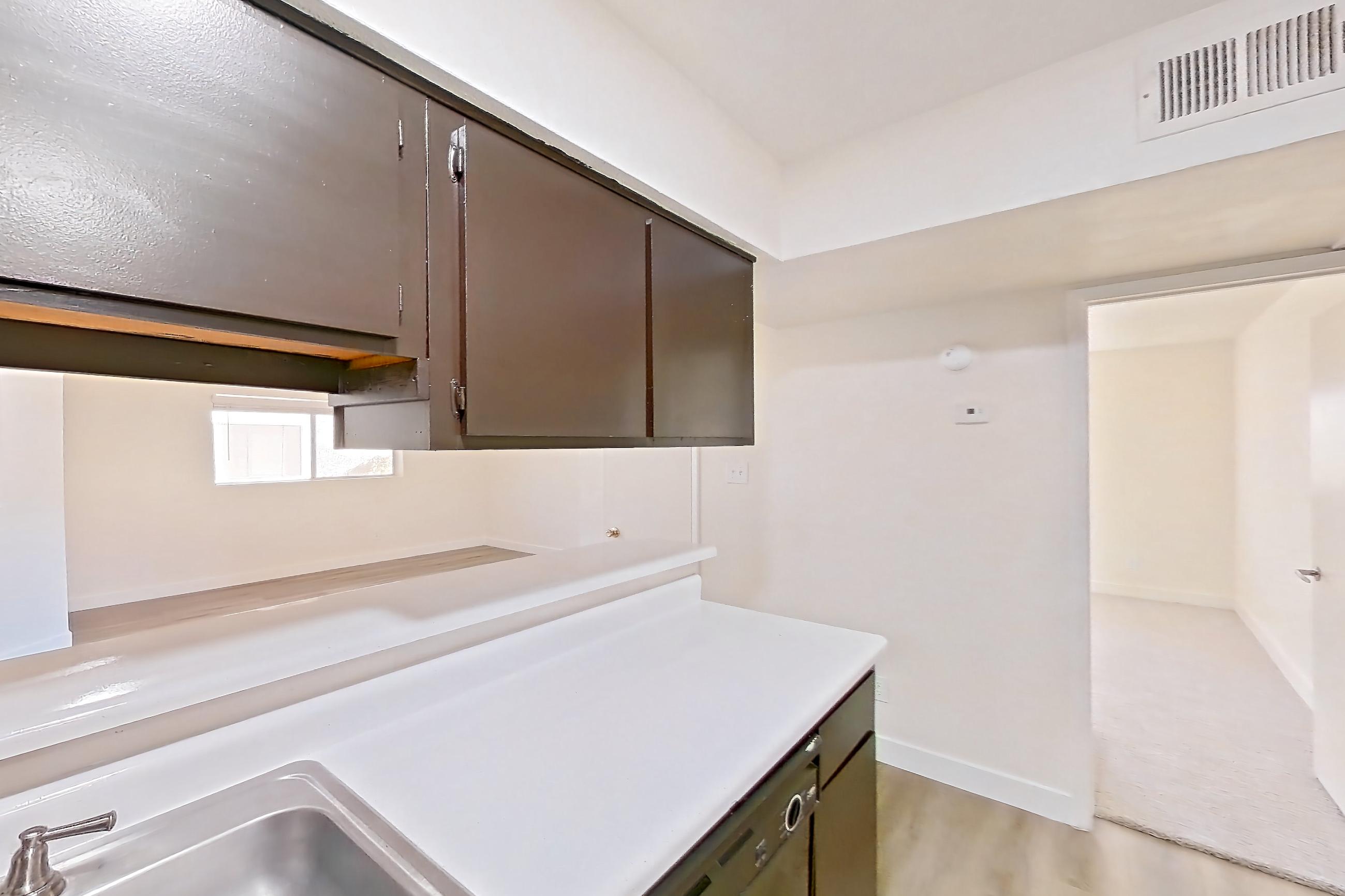 Kitchen with black appliances, dishwasher, electric range, light countertops, light wood-finish flooring, oven/range, range hood, and refrigerator, Apartment 1061 at Terra Vida Apartments