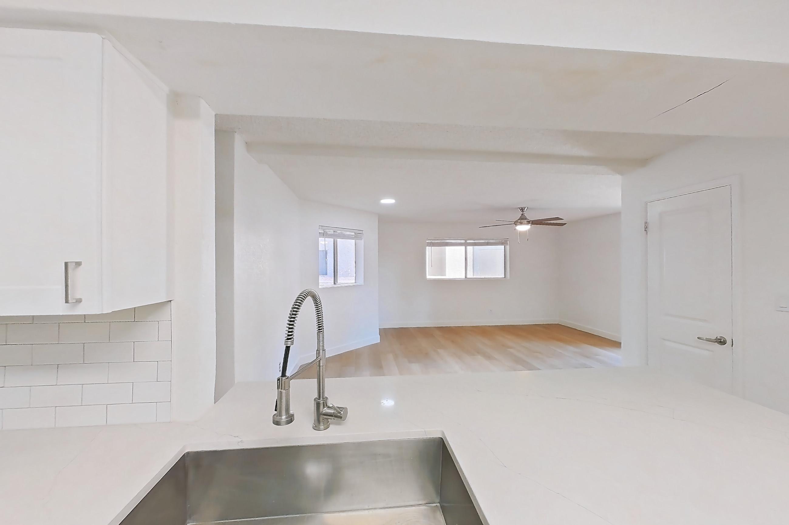 Kitchen with dishwasher, electric range, light countertops, light stone countertops, light wood-finish flooring, microwave, oven/range, refrigerator, and stainless steel appliances, Apartment 1091 at Terra Vida Apartments
