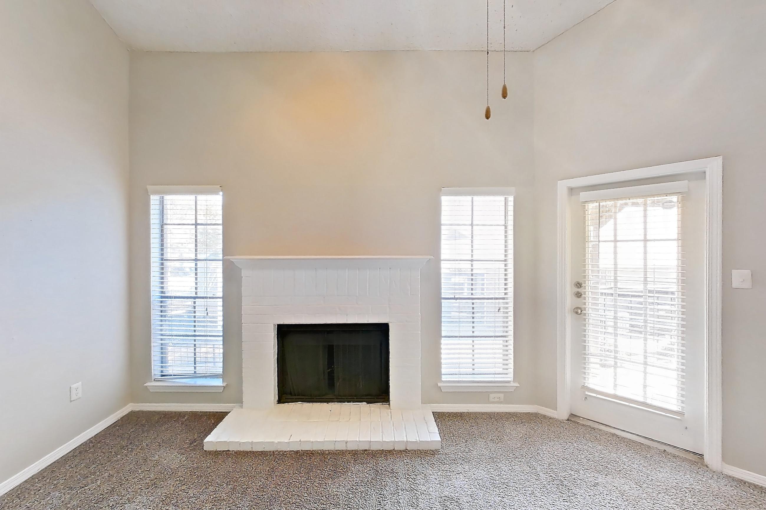 Living room with brick fireplace and fireplace, Apartment 08-0821 at The Arbors of Las Colinas