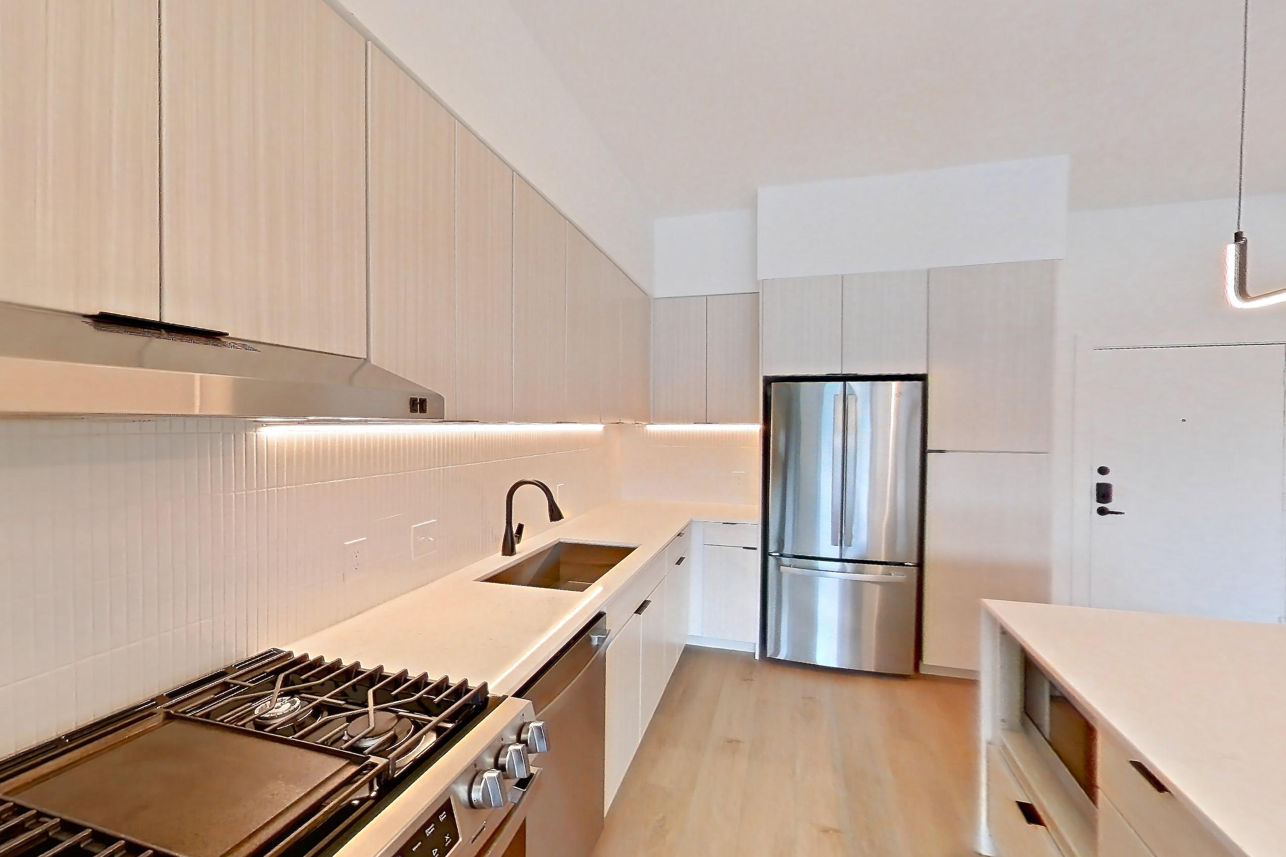 Kitchen with dark countertops, gas range, light stone countertops, light wood-finish flooring, oven/range, refrigerator, and stainless steel appliances, Apartment 0211 at Tempo at White Oak