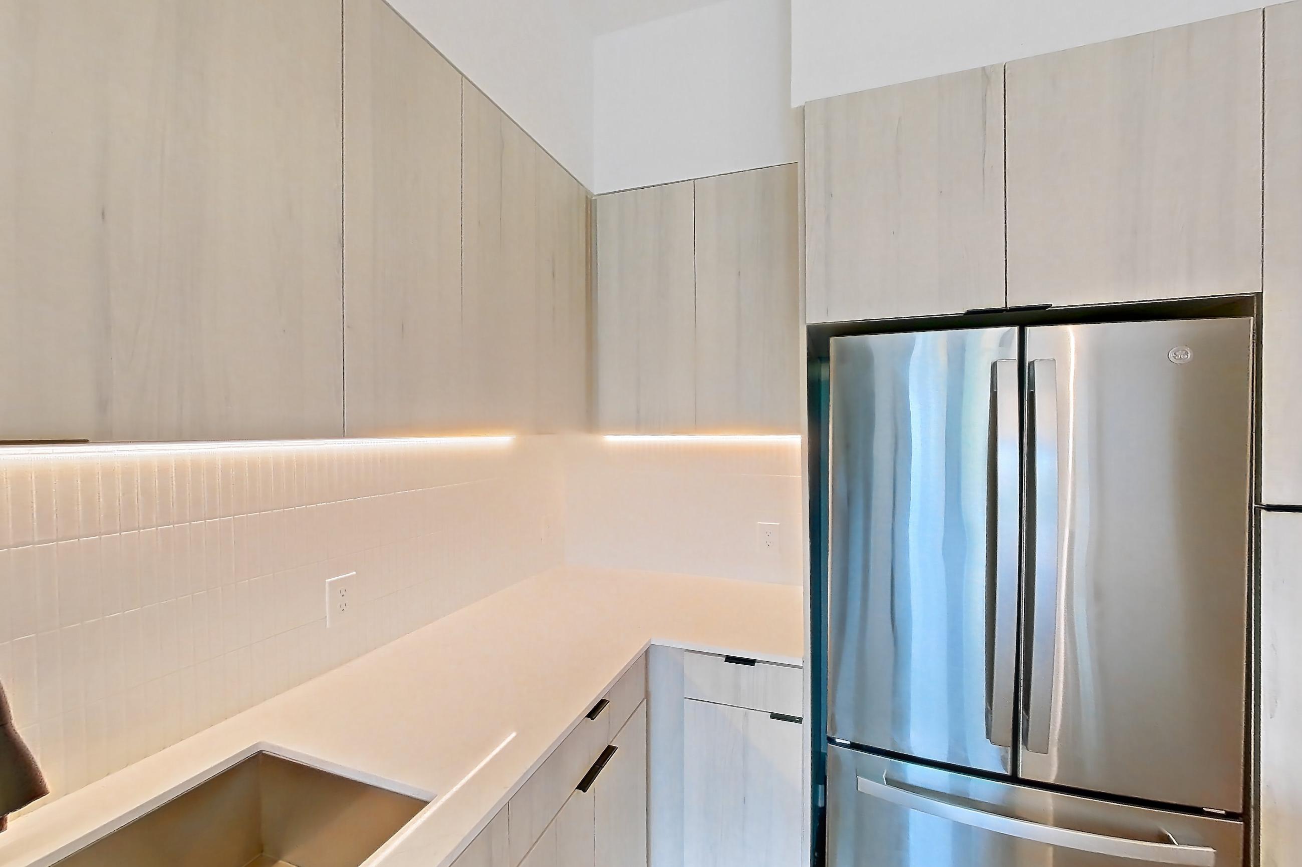 Kitchen with dishwasher, gas range, light stone countertops, light wood-finish flooring, oven/range, refrigerator, and stainless steel appliances, Apartment 0469 at Tempo at White Oak