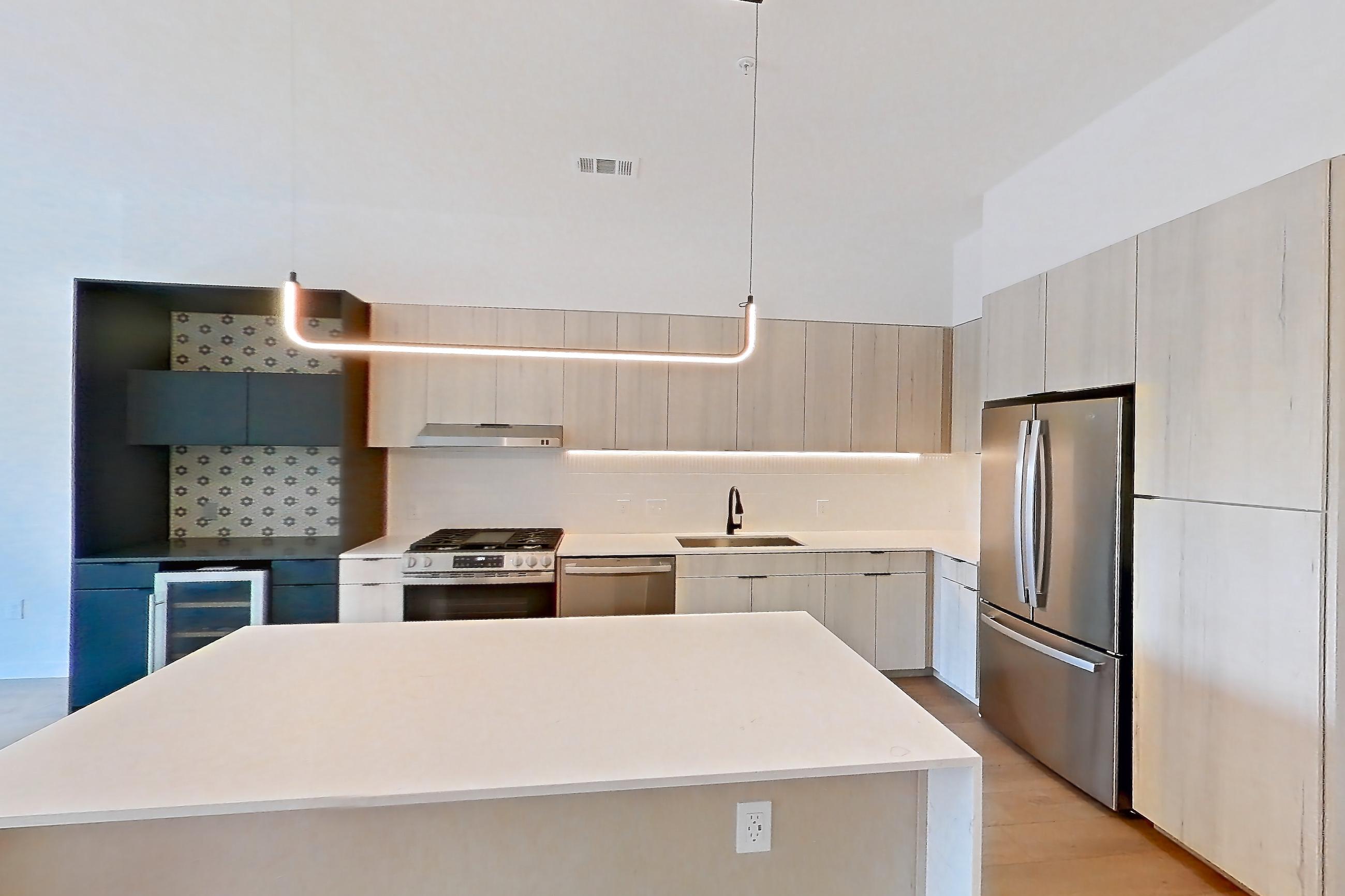 Living space with dishwasher, gas range, light stone countertops, light wood-finish flooring, oven/range, stainless steel appliances, and wood-finish flooring, Apartment 0469 at Tempo at White Oak