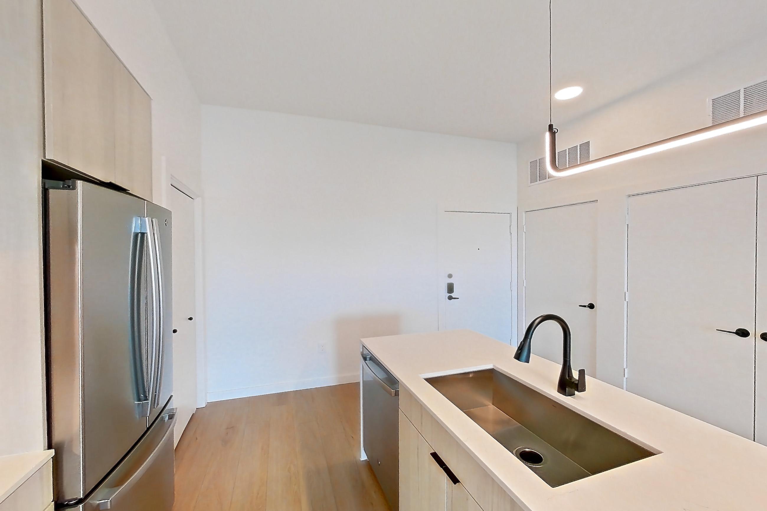 Kitchen with dishwasher, dry bar, gas range, light stone countertops, light wood-finish flooring, microwave, oven/range, range hood, refrigerator, stainless steel appliances, and wet/dry bar, Apartment 0445 at Tempo at White Oak