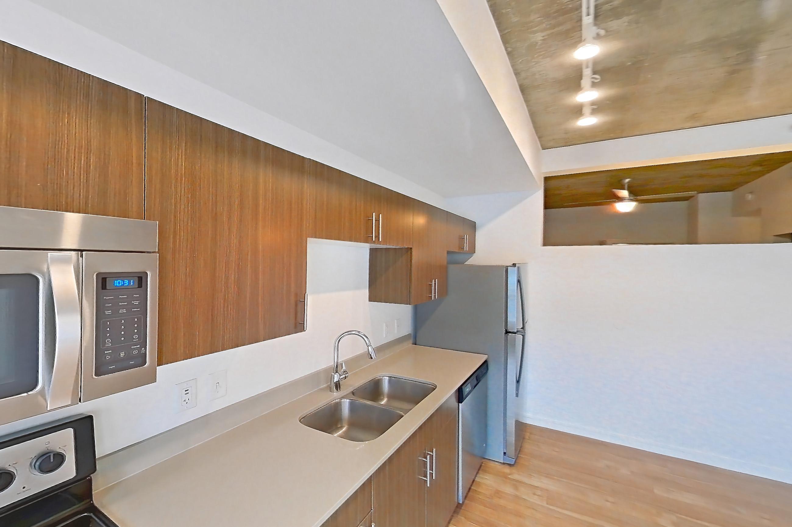 Kitchen with dishwasher, electric range, light countertops, light wood-finish flooring, microwave, oven/range, refrigerator, stainless steel appliances, and white appliances, Apartment 1013 at Cadence at Union Station