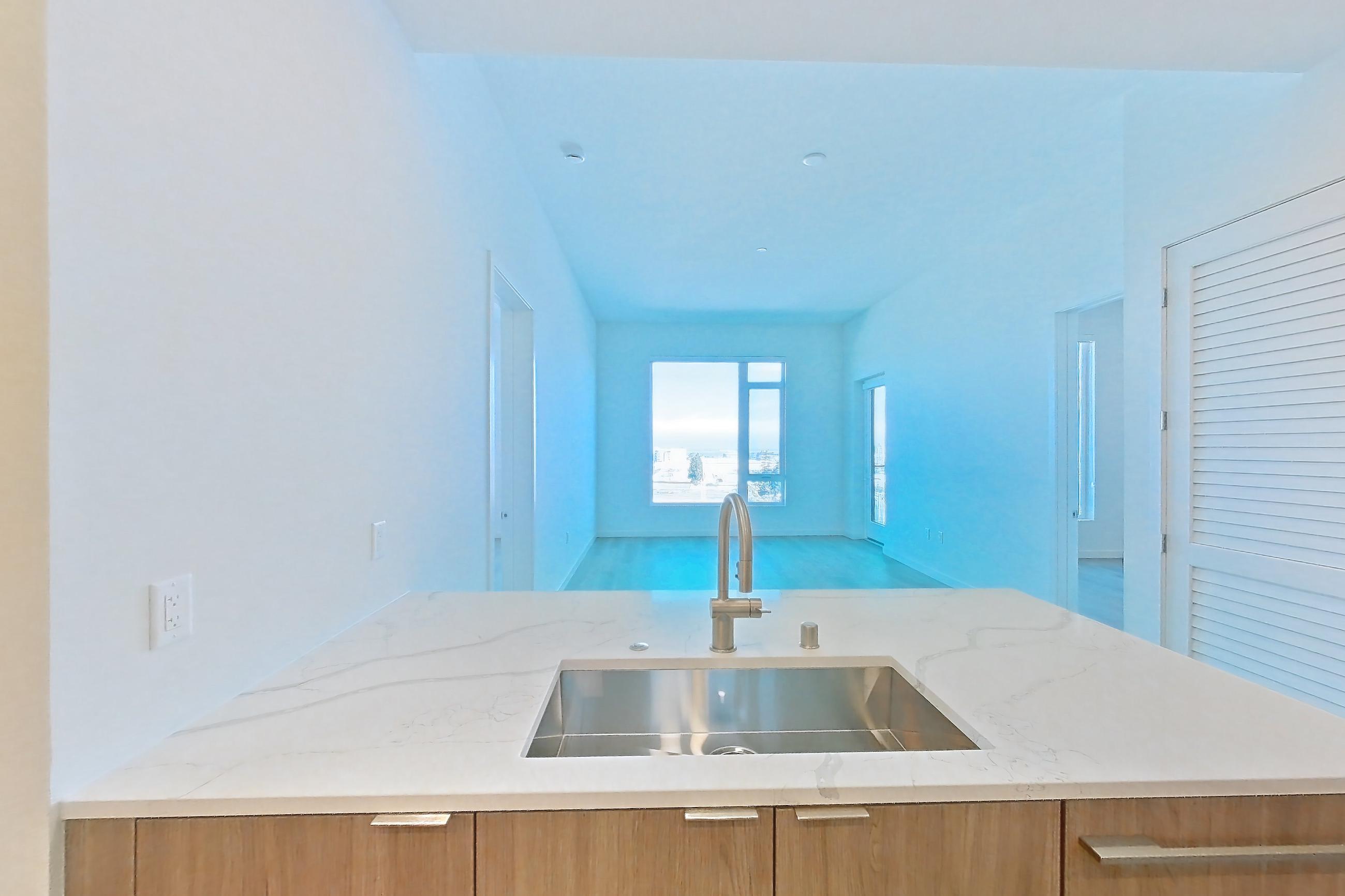 Kitchen with electric range, kitchen island, light stone countertops, light wood-finish flooring, oven/range, and stainless steel appliances, Apartment 816 at Revery