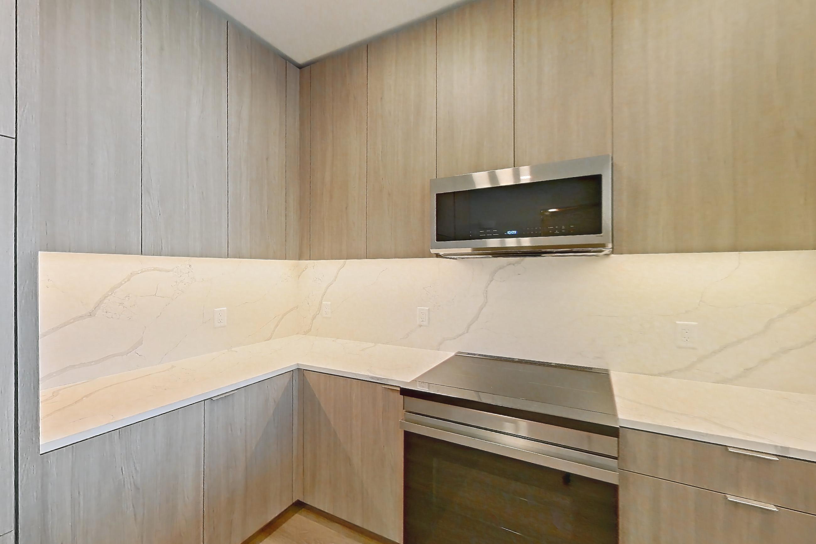 Kitchen with electric range, kitchen island, light stone countertops, light wood-finish flooring, oven/range, and stainless steel appliances, Apartment 816 at Revery