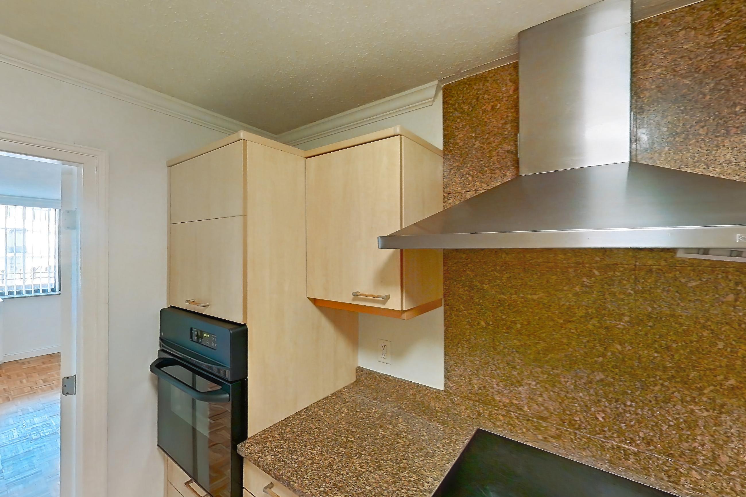Kitchen with black appliances, cooktop, dark stone countertops, electric cooktop, light tile flooring, microwave, oven/range, and stainless steel appliances, Apartment 221-0618 at Church Park
