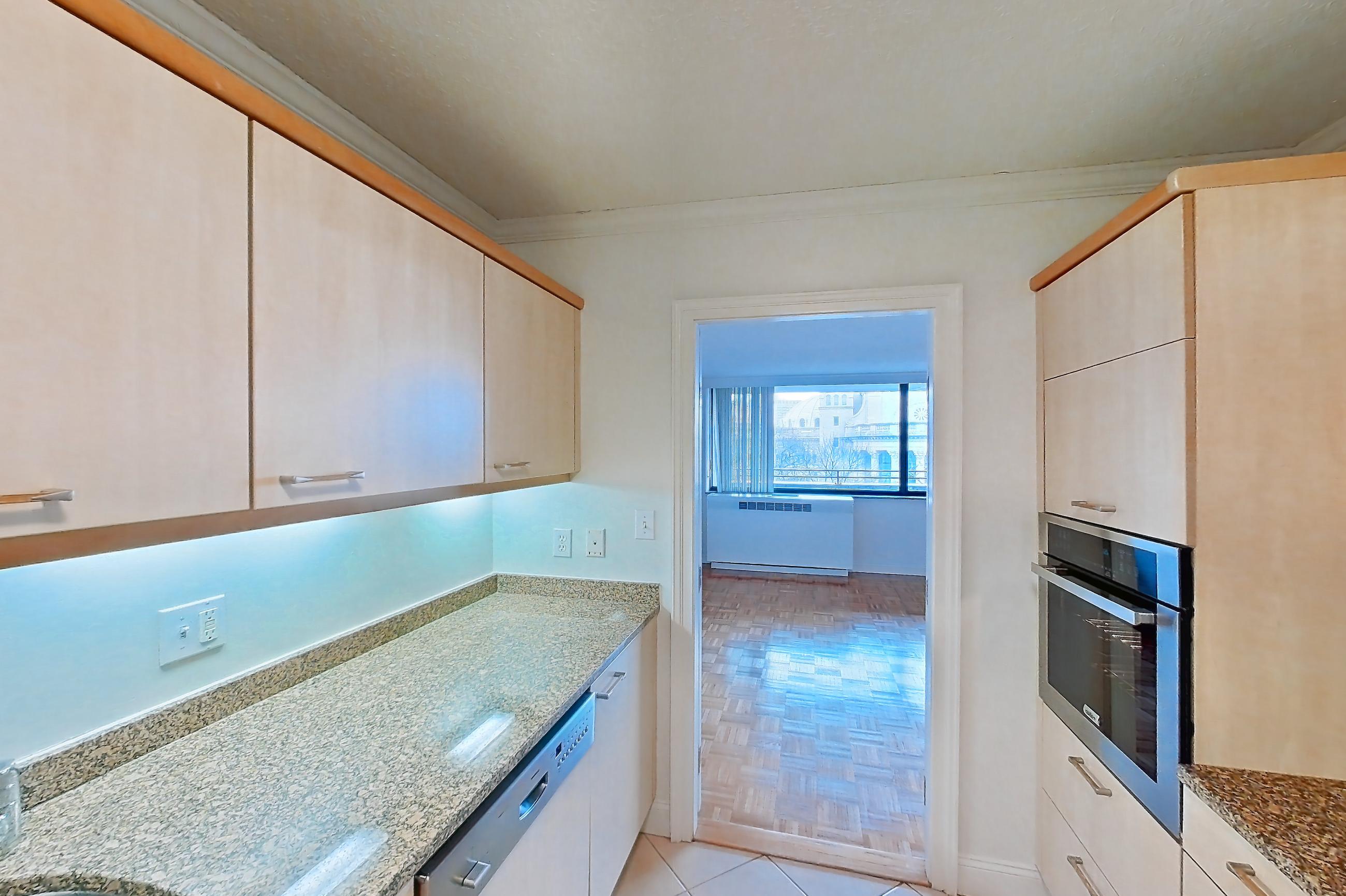 Kitchen with black appliances, cooktop, dark stone countertops, electric cooktop, light stone countertops, light tile flooring, and range hood, Apartment 255-0518 at Church Park