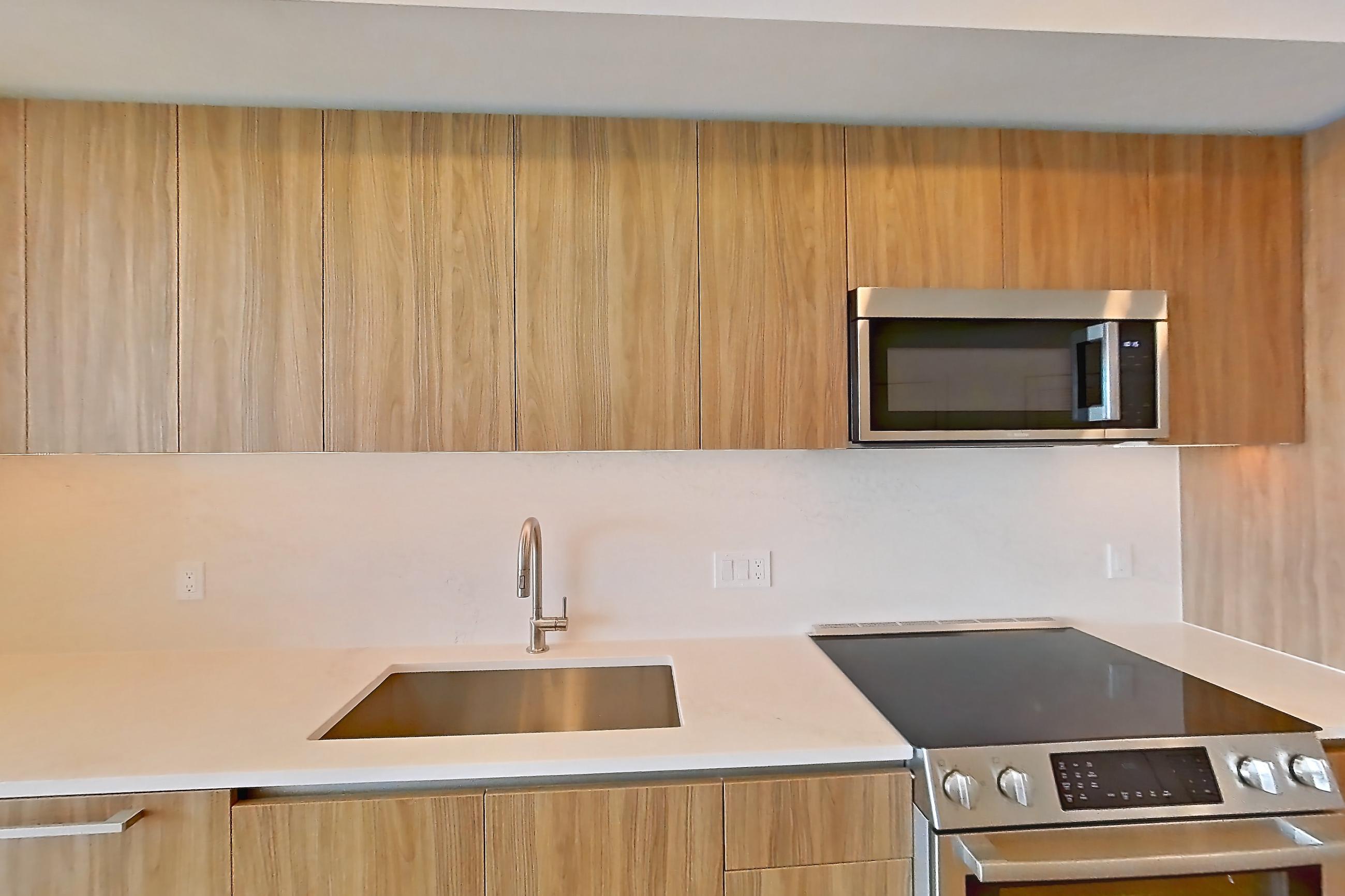 Kitchen with electric range, light stone countertops, light wood-finish flooring, oven/range, and stainless steel appliances, Apartment 1633 at Zephyr