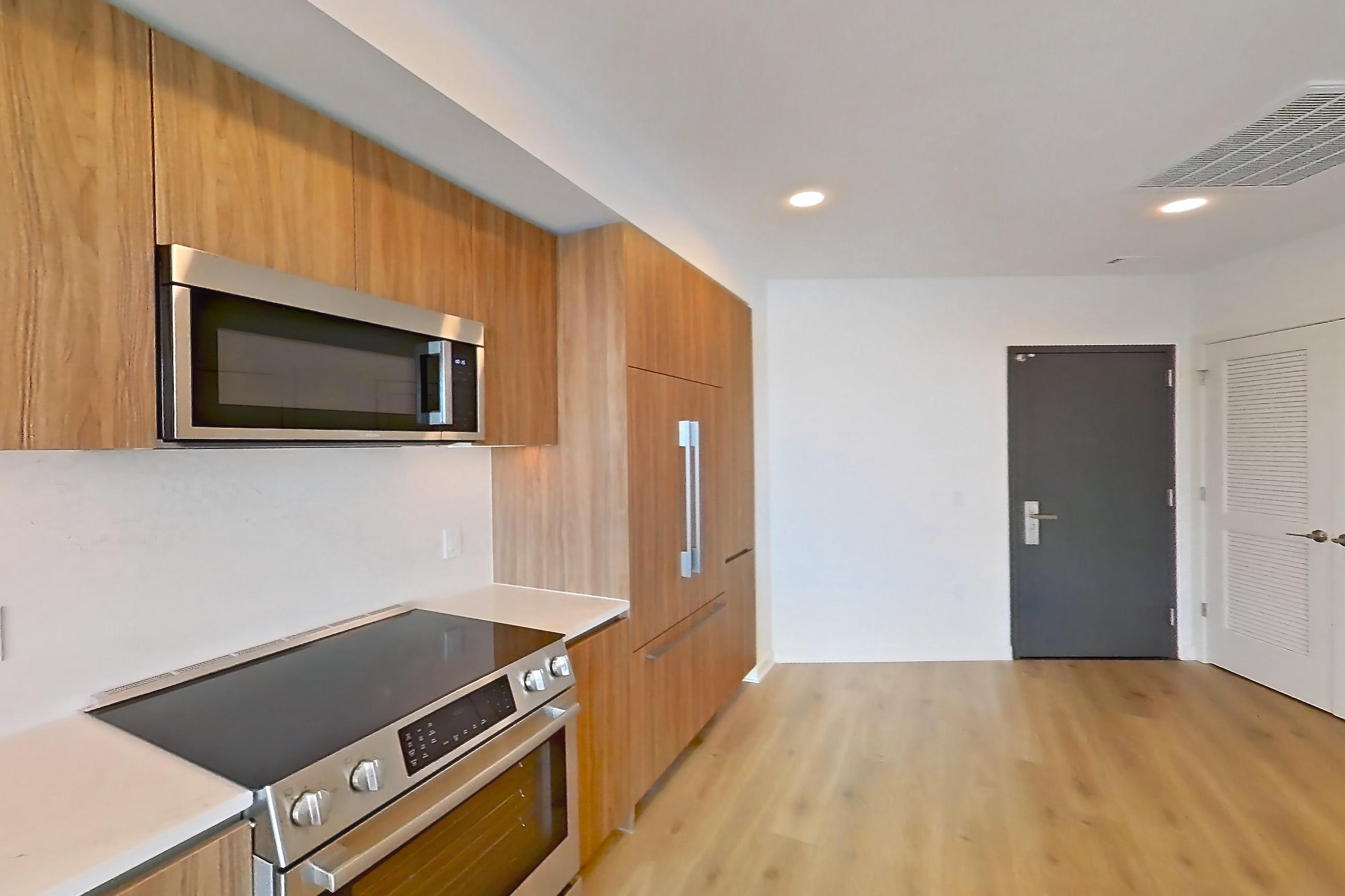 Kitchen with electric range, light stone countertops, light wood-finish flooring, oven/range, and stainless steel appliances, Apartment 1633 at Zephyr