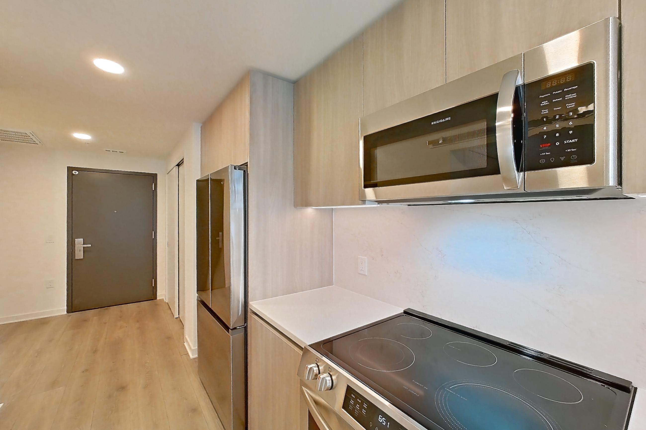 Kitchen with electric range, light stone countertops, light wood-finish flooring, oven/range, stainless steel appliances, and wood-finish flooring, Apartment 0822 at Zephyr